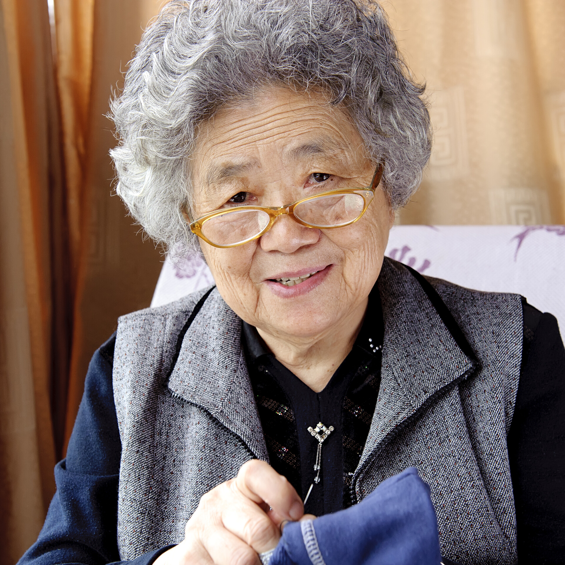 坐在沙发上缝衣服的奶奶缝纫的祖母