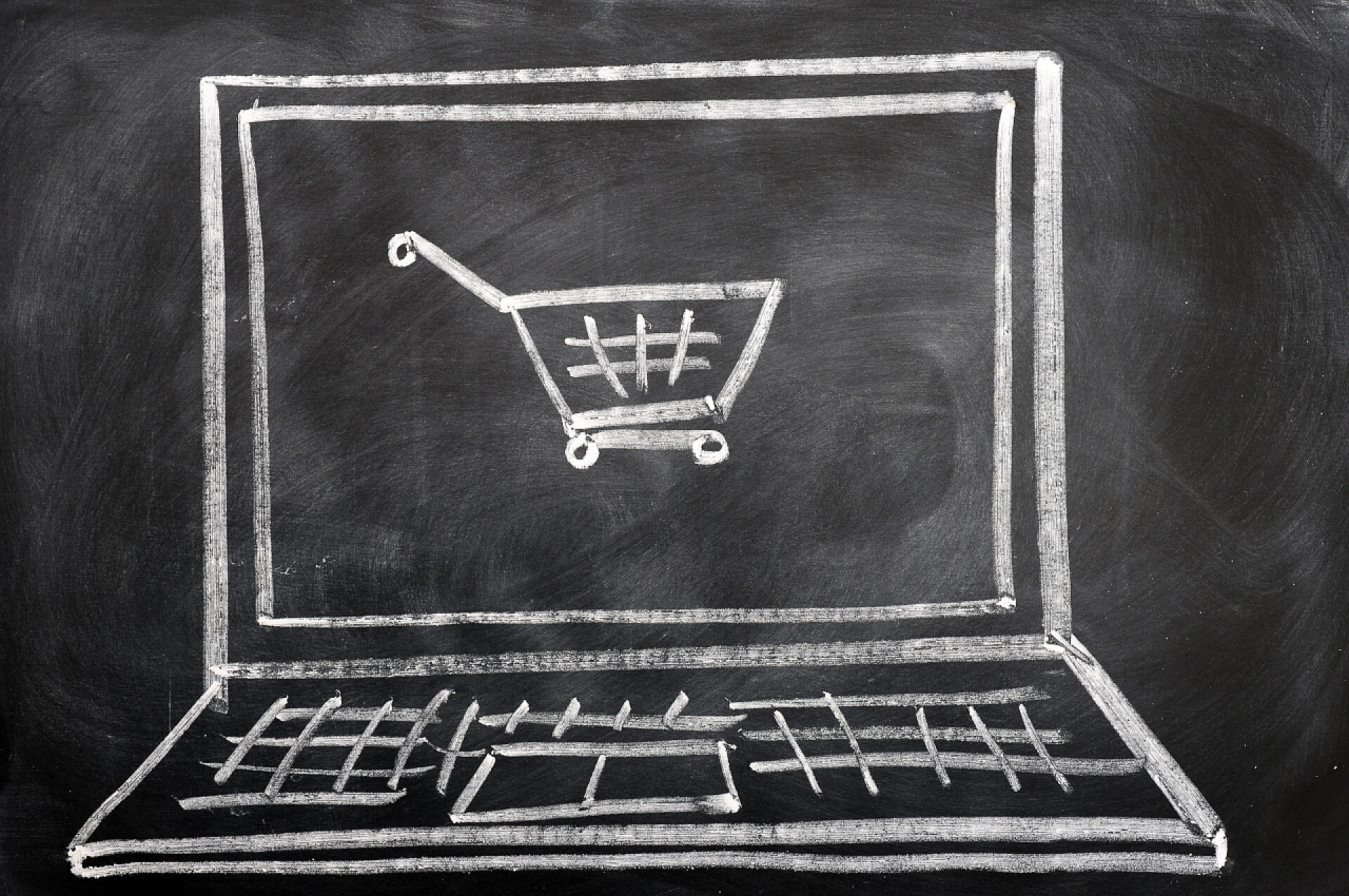 黑板上用粉笔勾勒的笔记本电脑和购物车线条电子商务概念