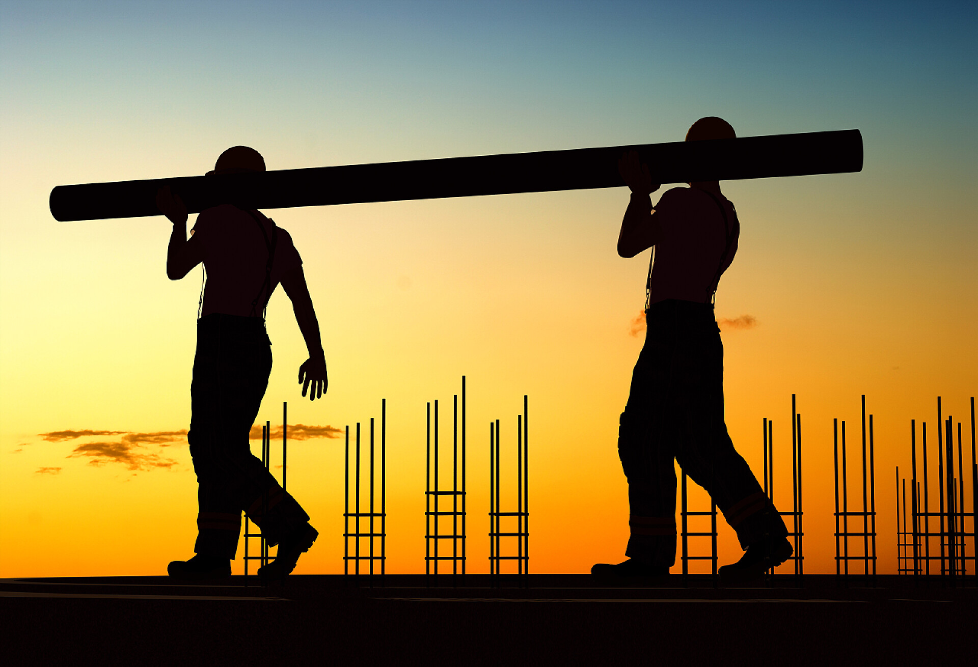 两名工人运输管道的剪影集团的工人进行管.