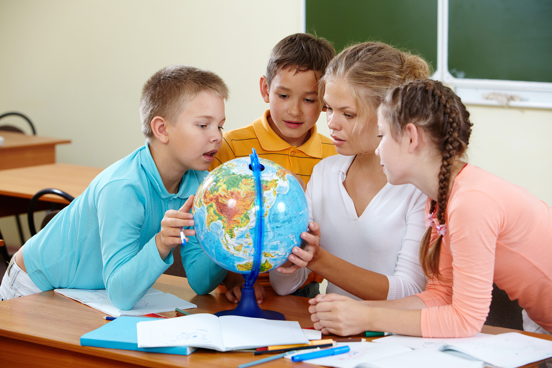 在教室里可爱的学生和老师看着地球仪学习的星球