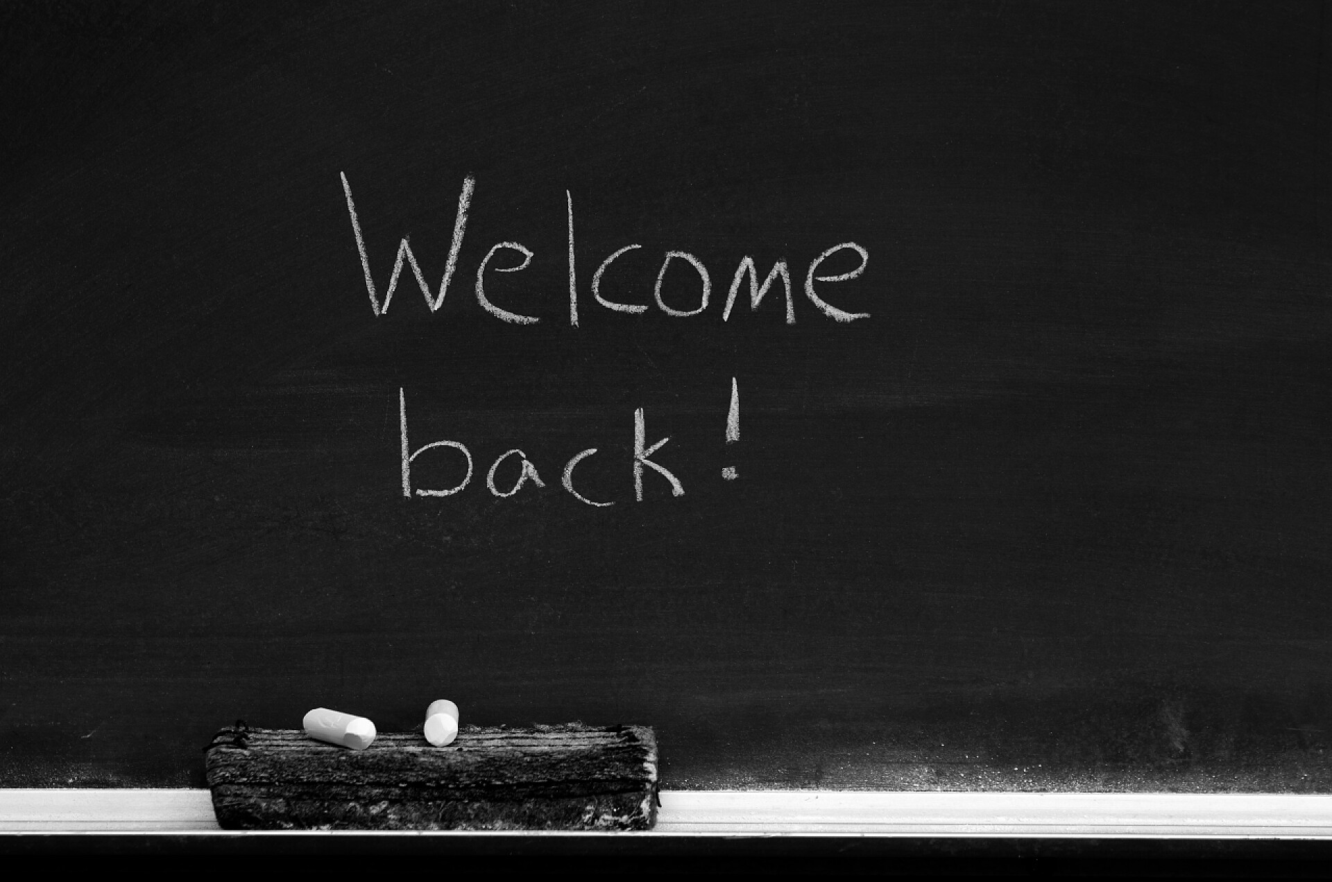 白色粉笔橡皮擦与黑板欢迎回迹象与黑板黒板の後ろのサインへようこそ