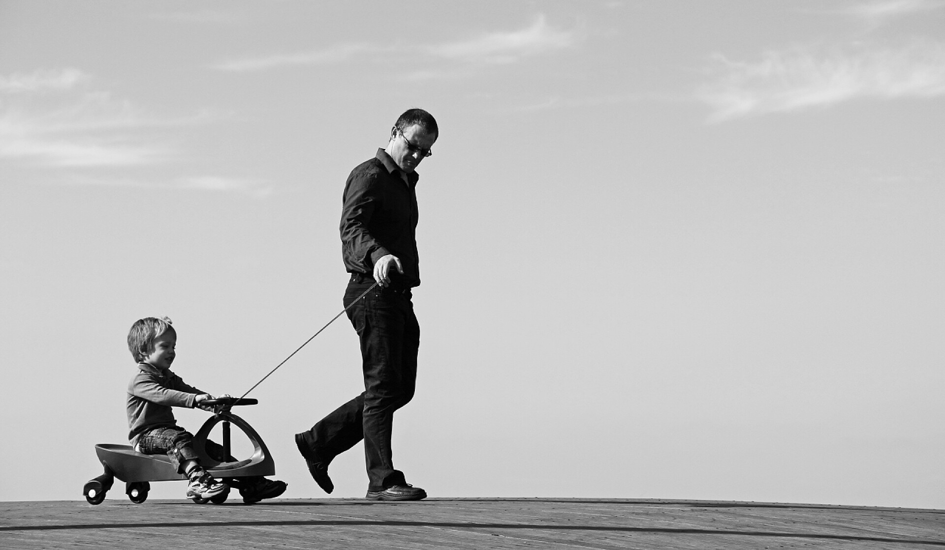 父亲拖着孩子坐滑板车父亲和儿子一起度过空闲时间