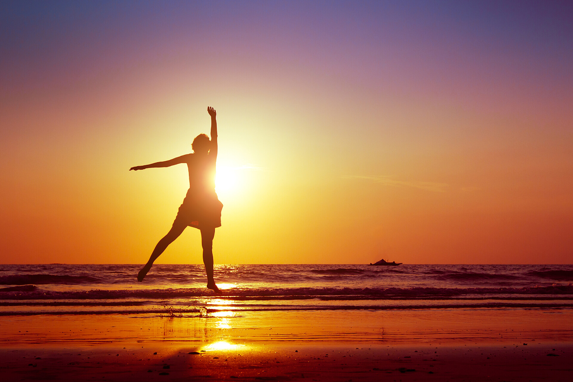 在落日的余晖下女人在海滩上跳舞跳跃的女人