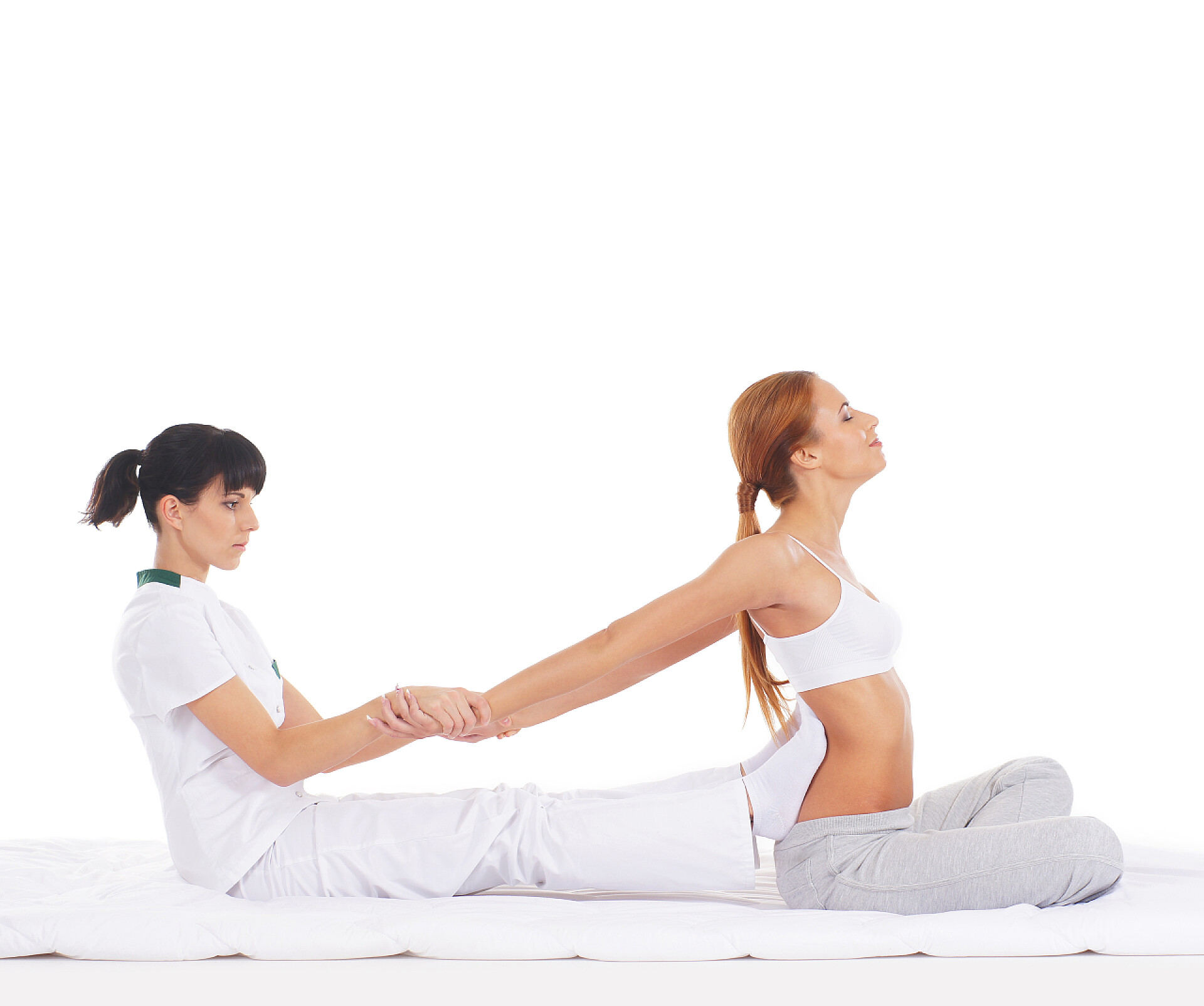 在白色背景上给女人做拉伸的泰式按摩师一个年轻的红发女人在泰式按摩程序