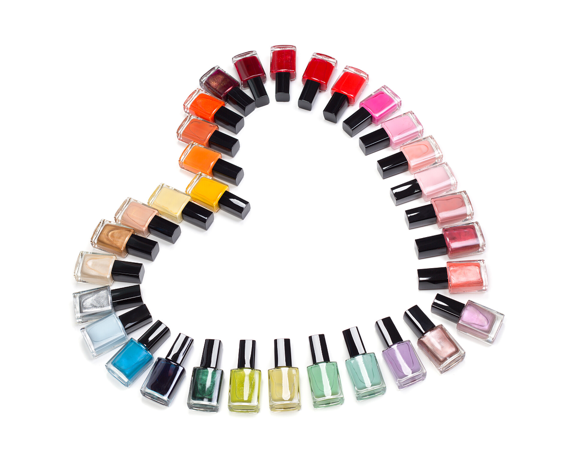 白色背景上五彩指甲油组成的心形五彩的瓶的指甲油形式的心