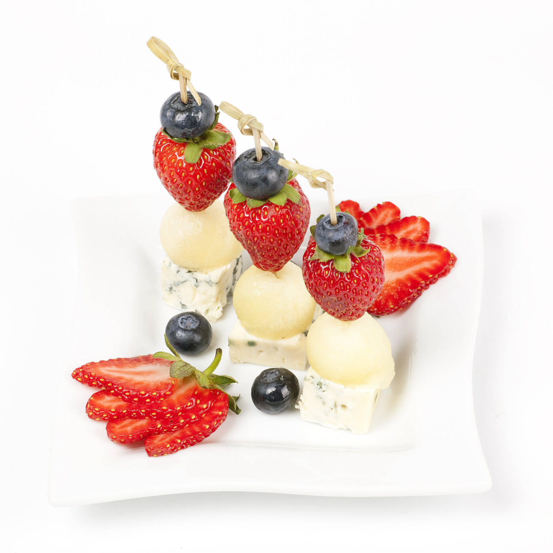 白色背景上盘子里的水果和奶酪蛋糕面包与奶酪甜瓜和草莓的板上