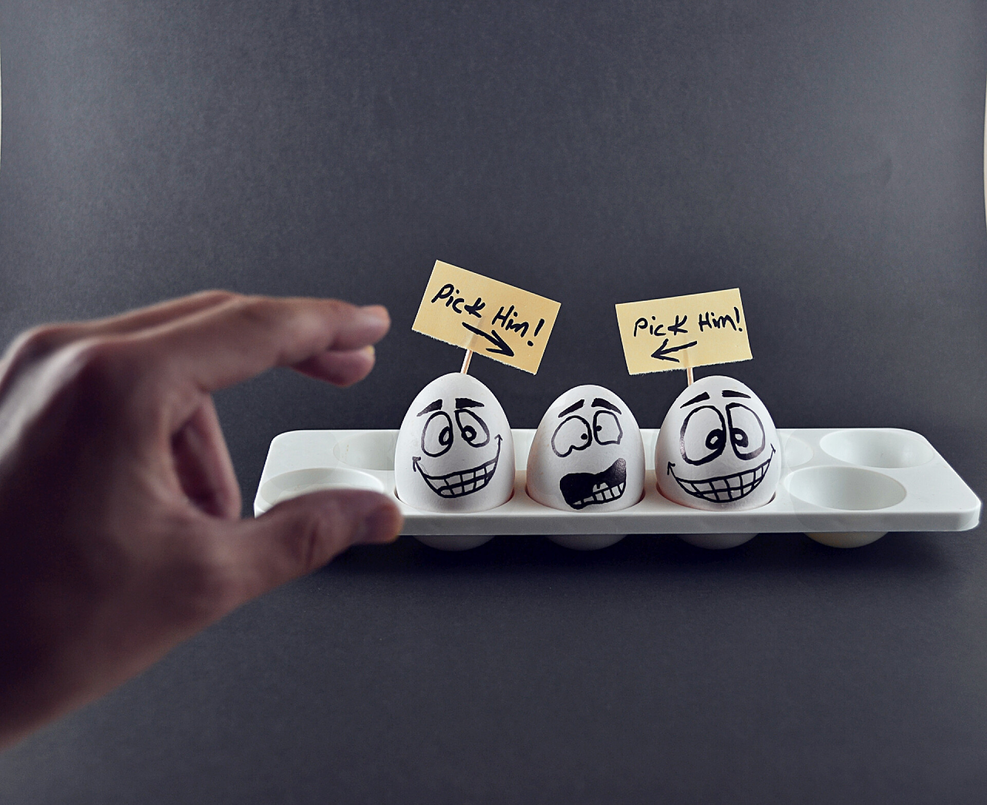 黑色背景上手去拿白色搞笑鸡蛋特写搞笑的鸡蛋