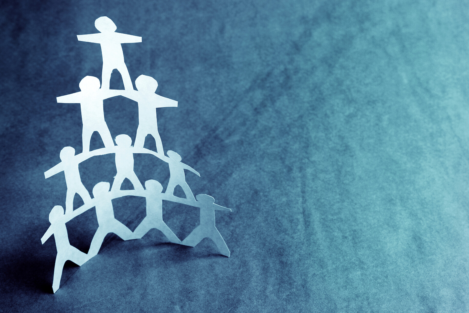 蓝色背景小纸人堆叠成三角形的形状团队