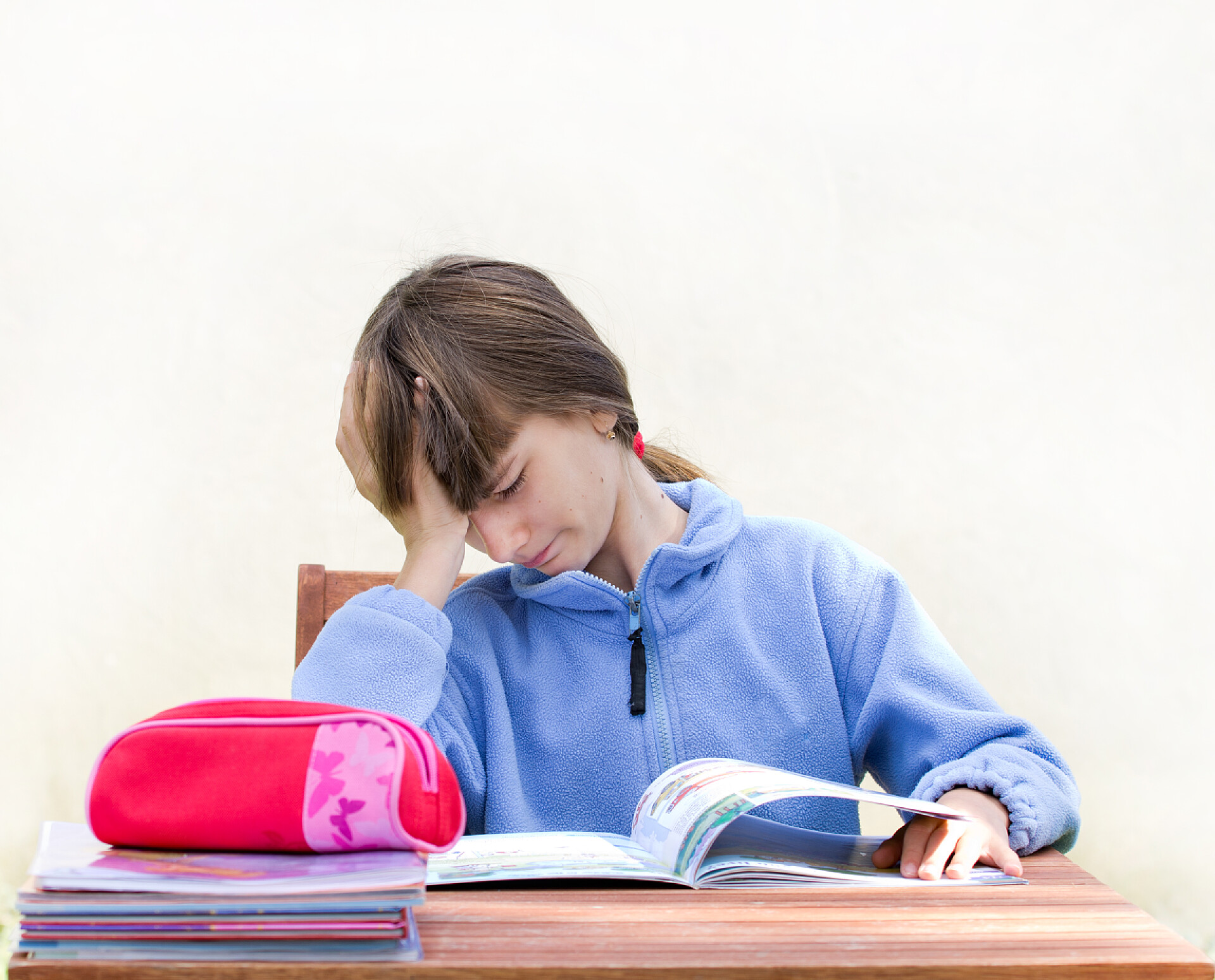 在白色背景上可爱女孩手拖着脑袋看书家庭作业