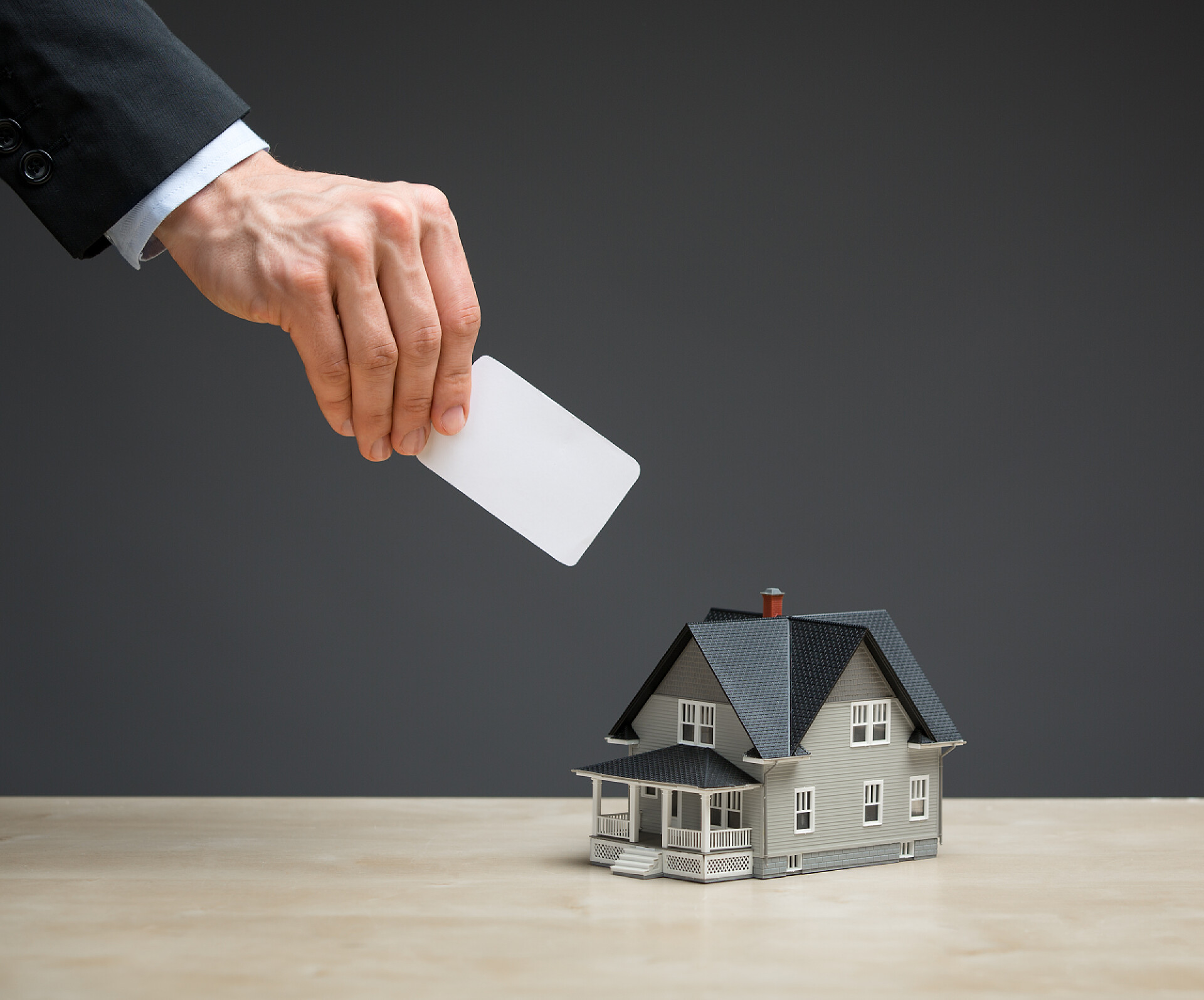 手拿银行卡存进银行投资小房子和手的特写