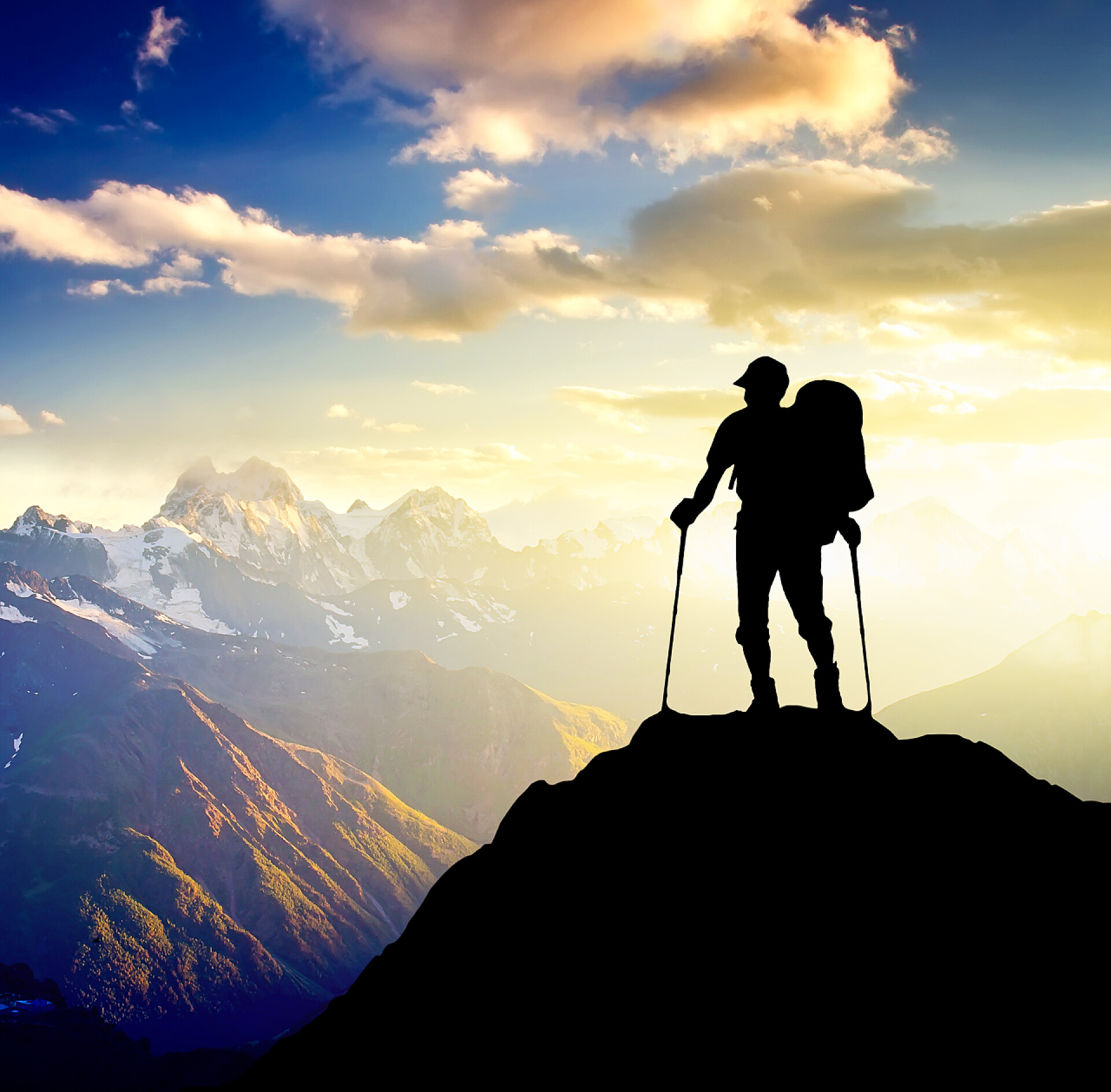 太阳光芒下登上山顶的人物轮廓在太阳的光芒背景的人的剪影