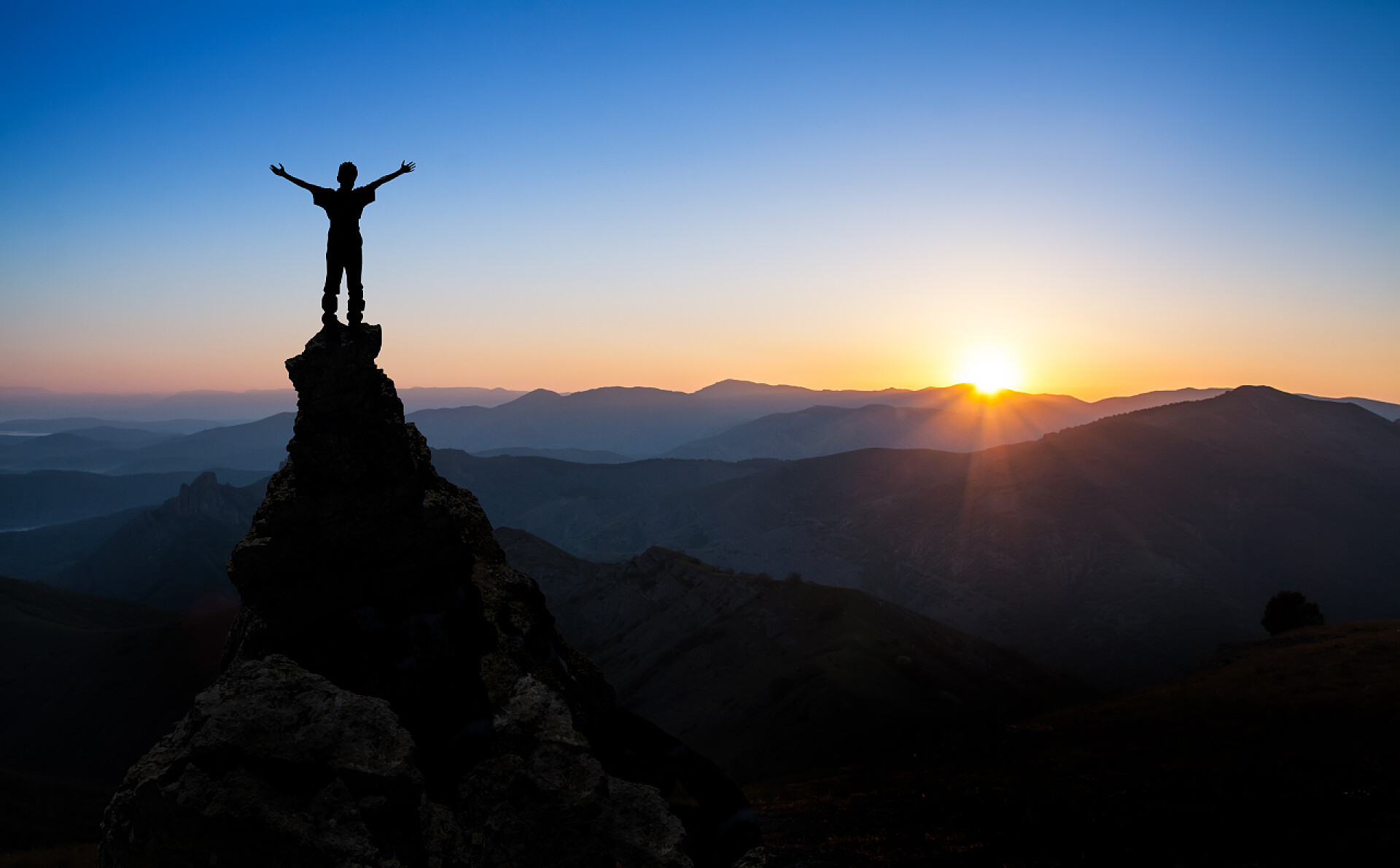 落日下爬上山顶的男人概念成功、 体育、 胜利