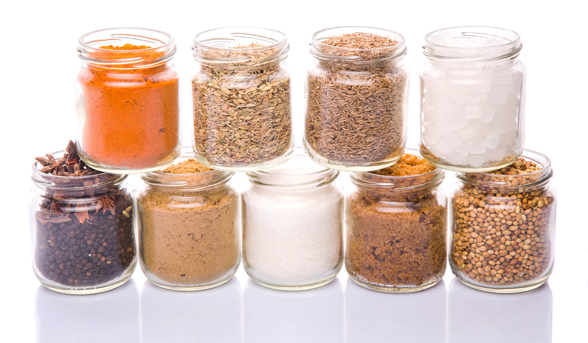 白色的背景上不同种类的香料瓶子糖和香料