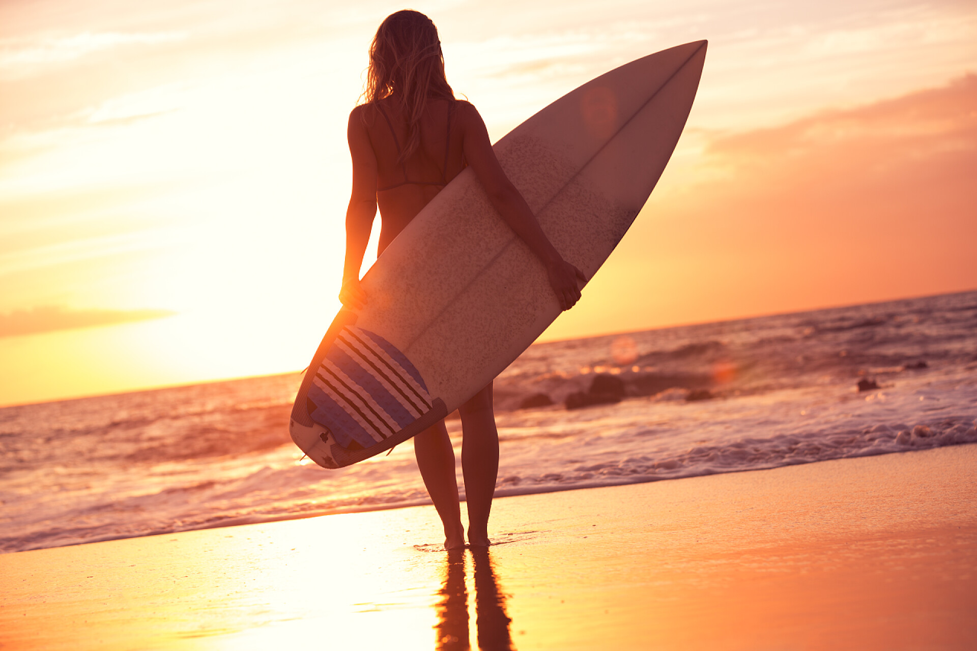 日落海滩上冲浪女孩的剪影剪影冲浪女孩