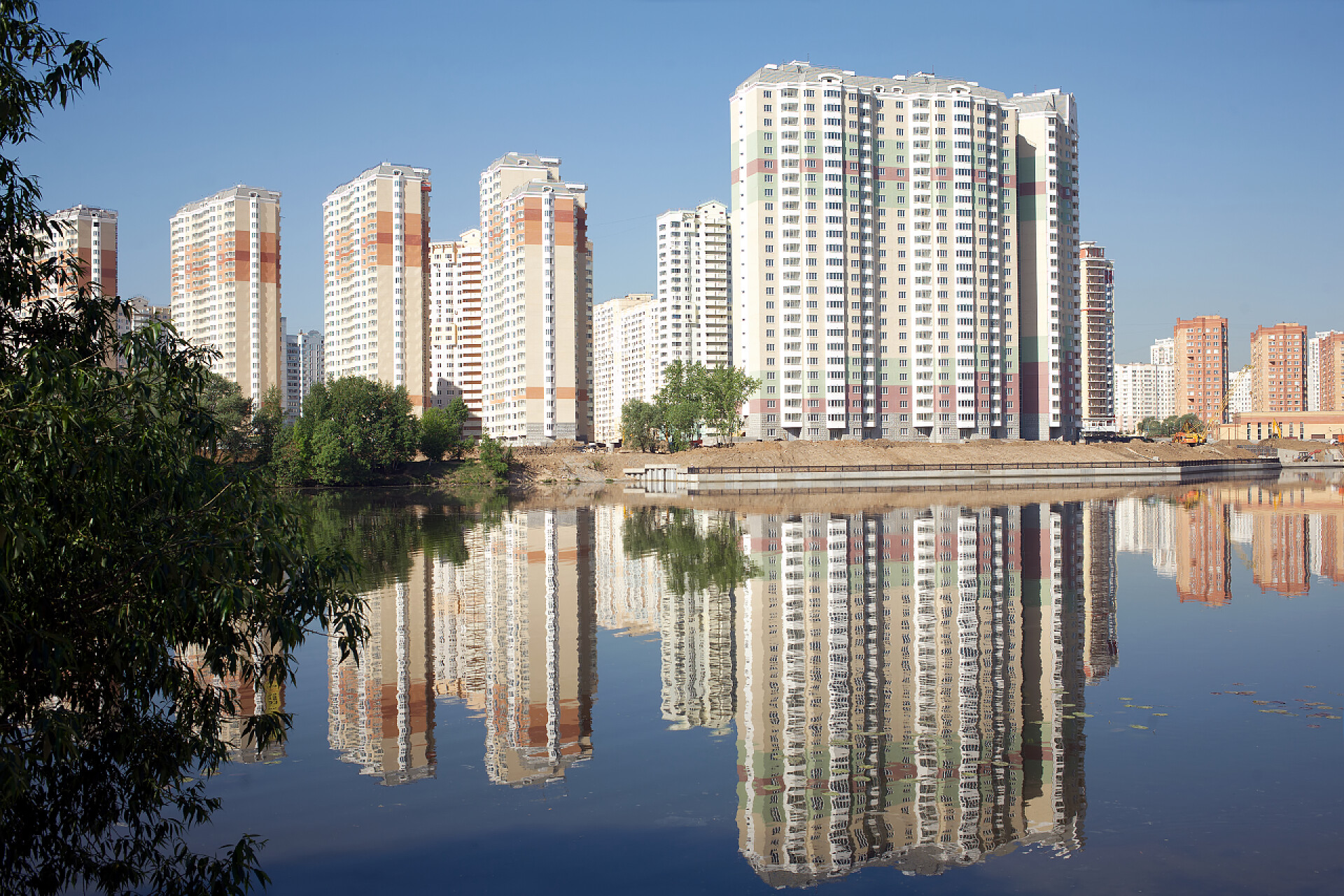 清澈河水中公寓楼的倒影构造的块的屋河和湛蓝的天空，在夏季的一天