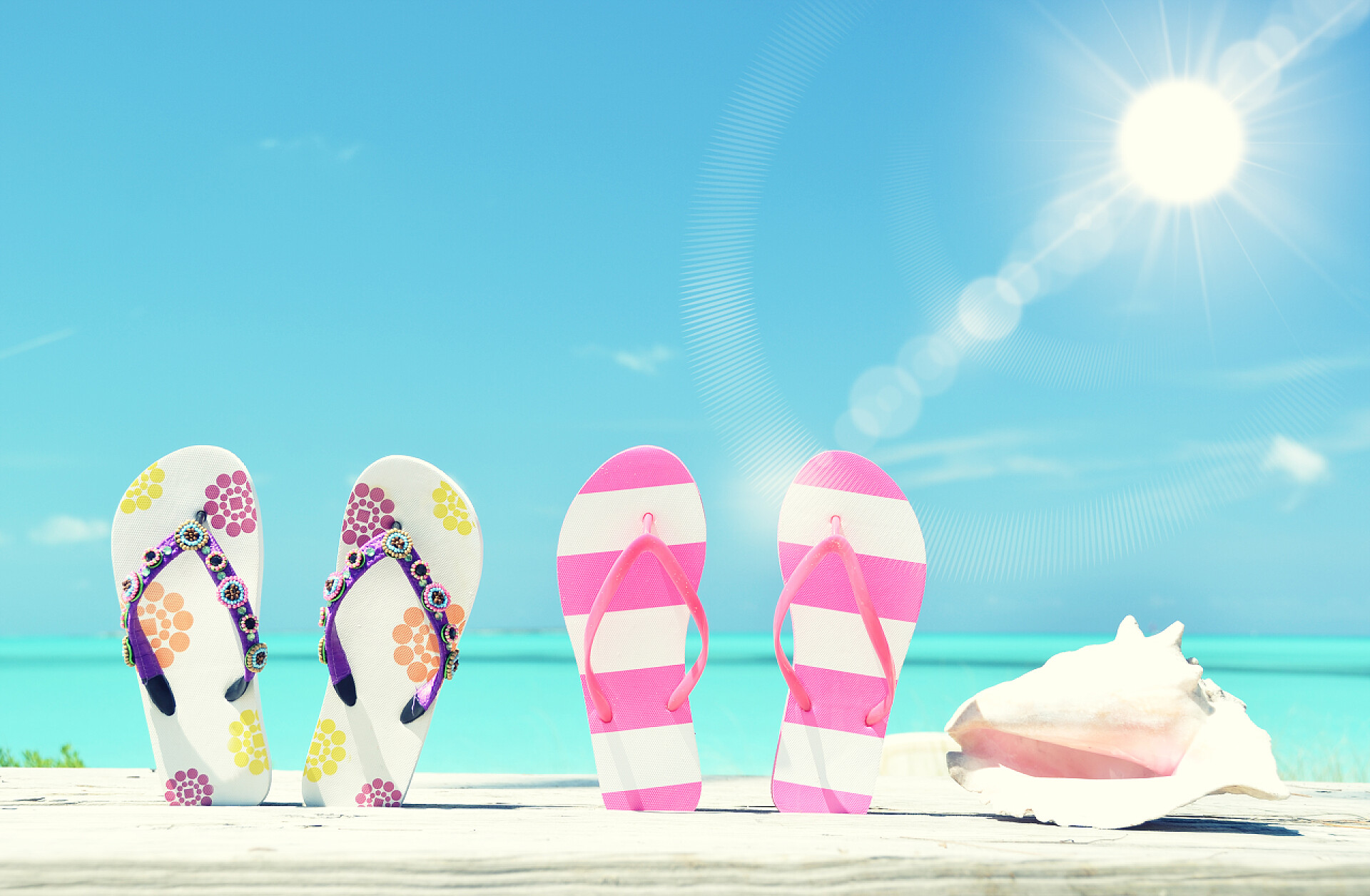 沙滩上的两对人字拖鞋两个成对的拖鞋和外壳