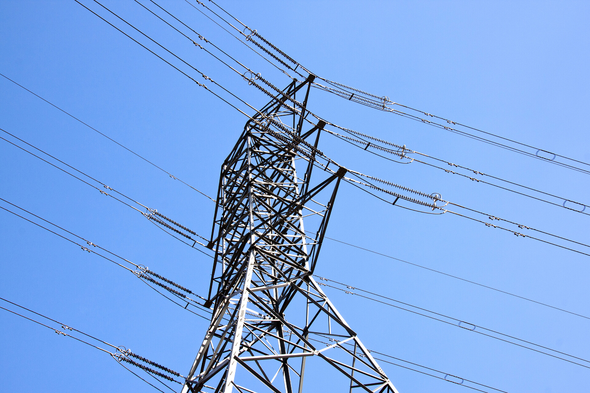 仰拍蓝蓝的天空下电缆电线特写钢制挂架支持重型电力电缆 