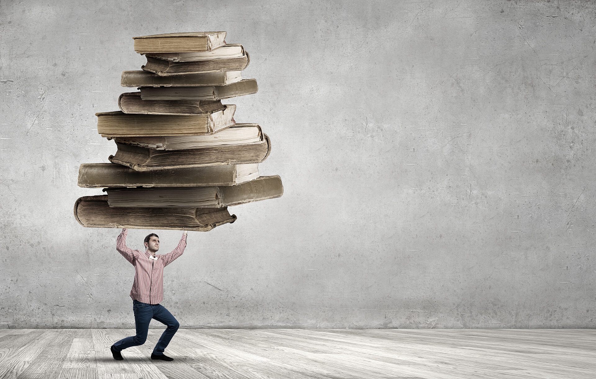 一位年轻的男人举起一堆旧书籍我要努力学习