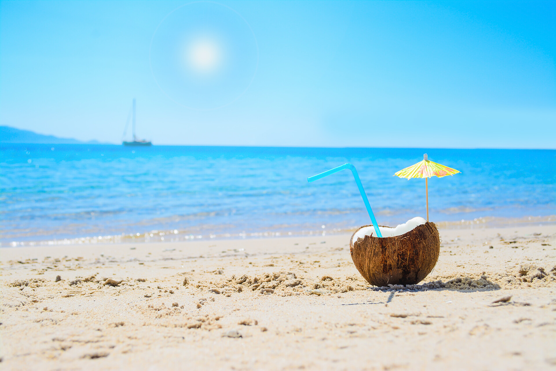 海滩边的椰子上有吸管和小伞阳光下的椰子