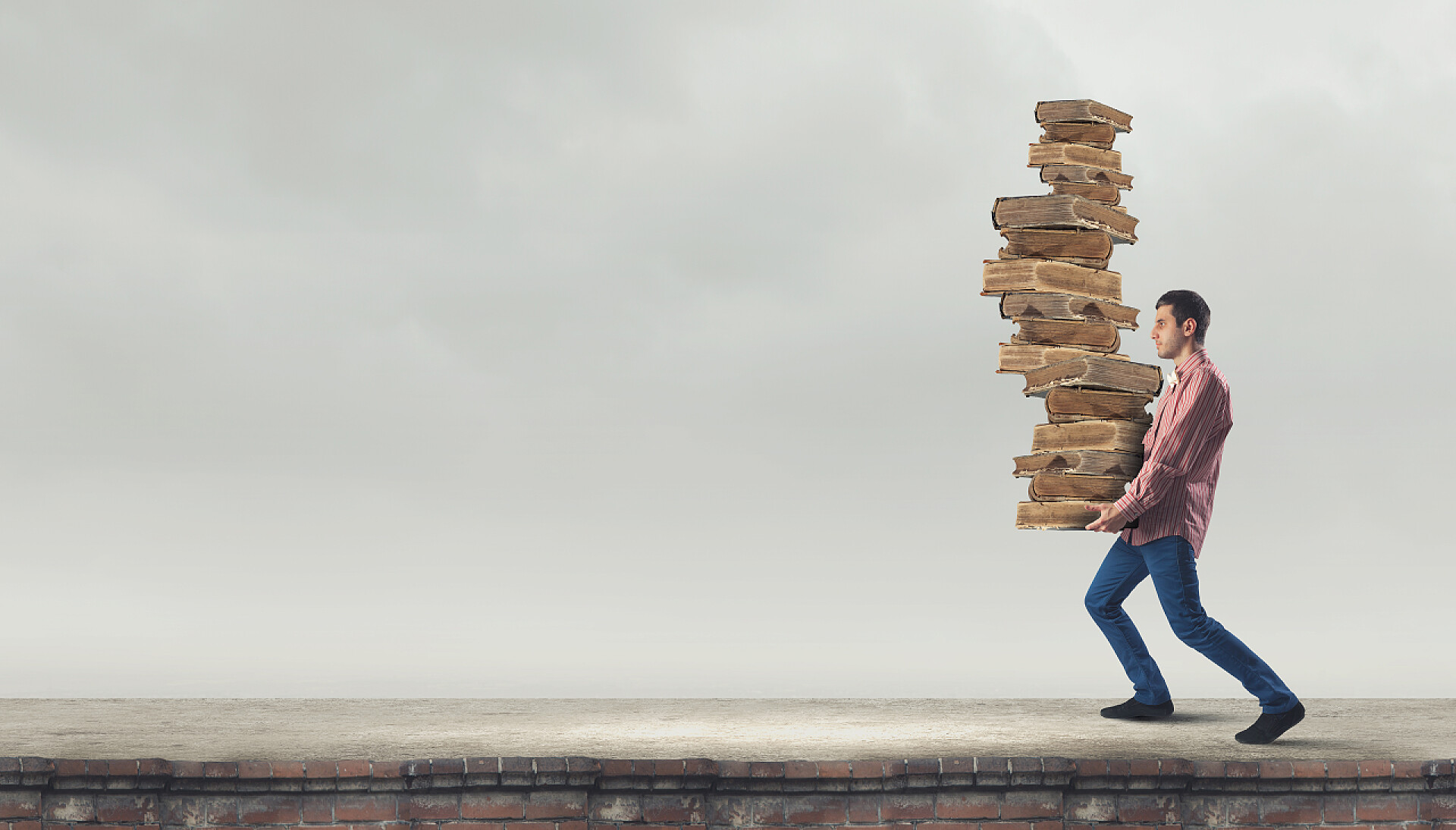 灰色天气下抱着堆高的旧书籍得年轻人我要努力学习