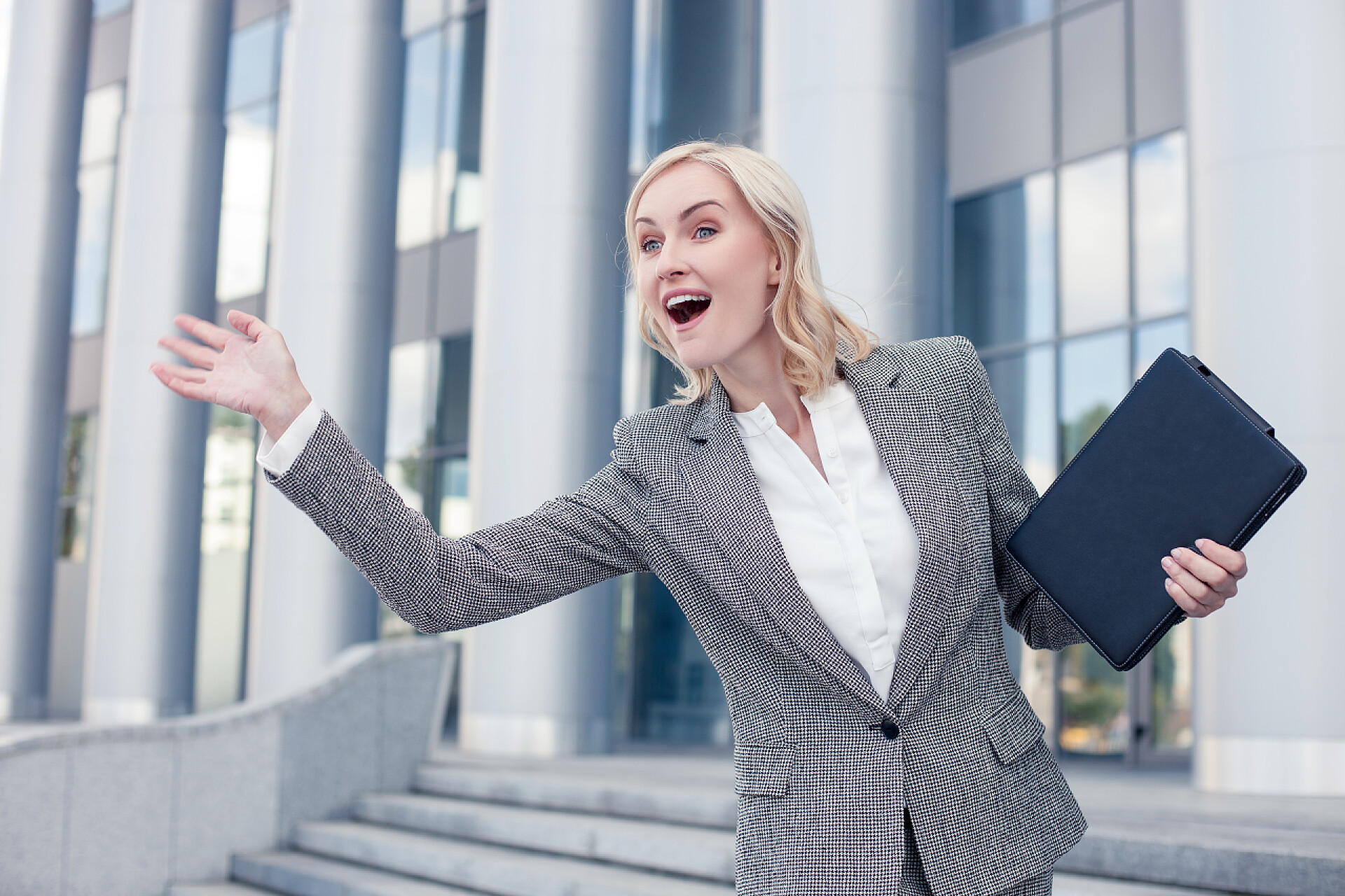 商务楼外的女商人在和别人打招呼Cheerful young woman is greeting her business partner