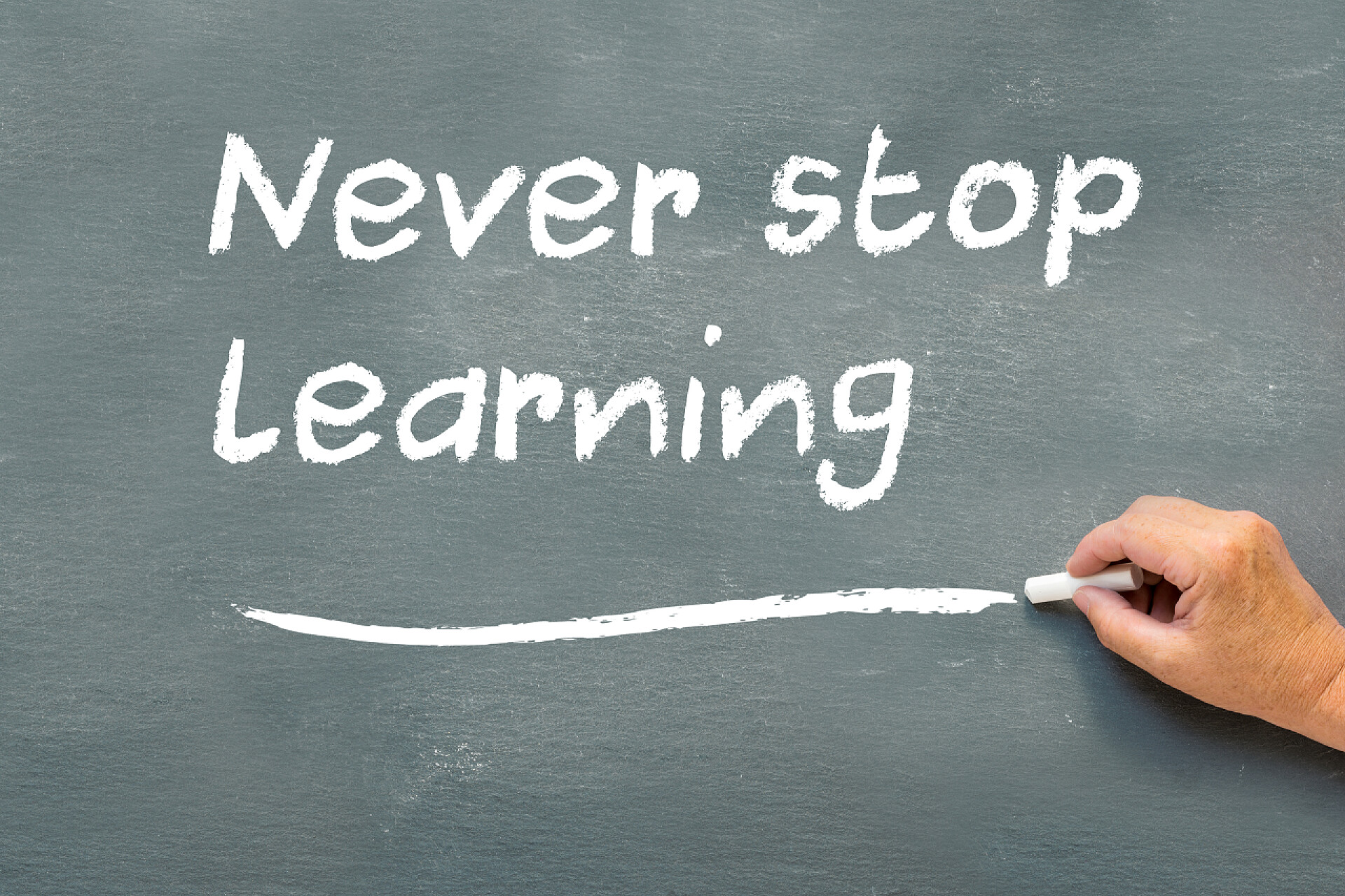 在黑板上写下永远不会停止学习的单词手在黑板上的书写永远都不要停止学习