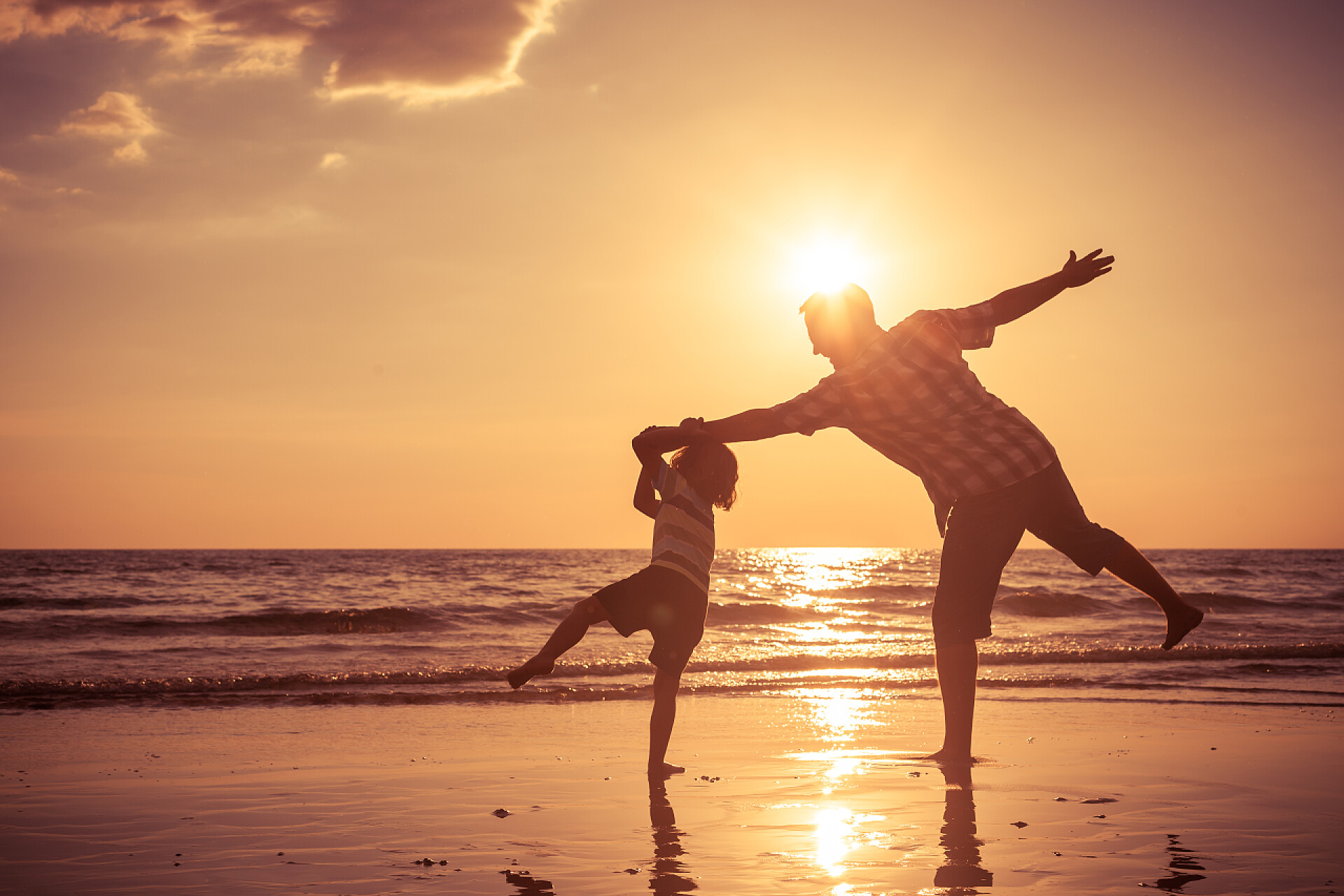 日落时分父亲带孩子在海滩玩耍父亲和儿子在日落的时候在海滩上玩.