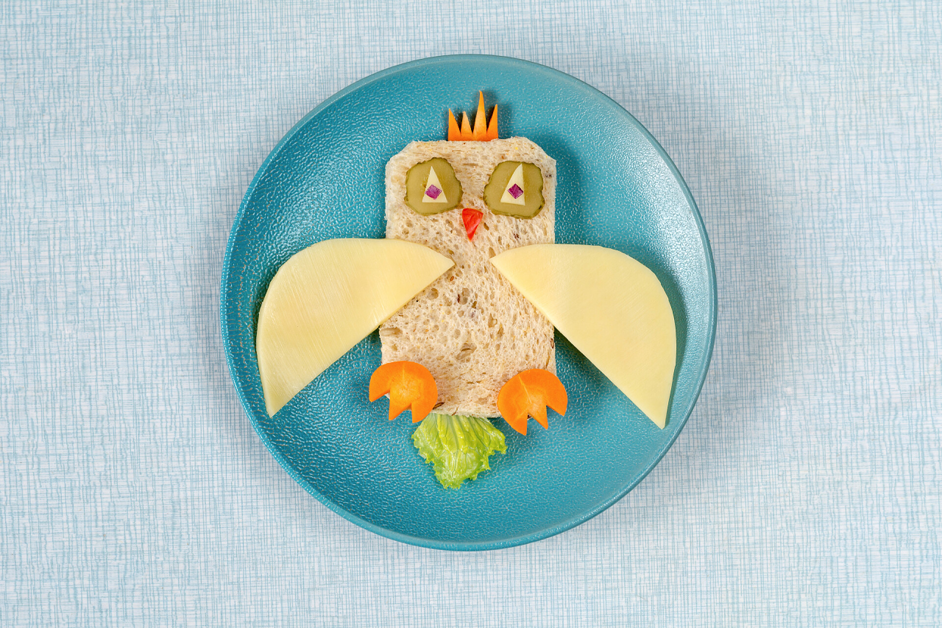 蓝色背景下一盘猫头鹰形状的儿童套餐对于孩子来说，健康午餐有趣夹心板上