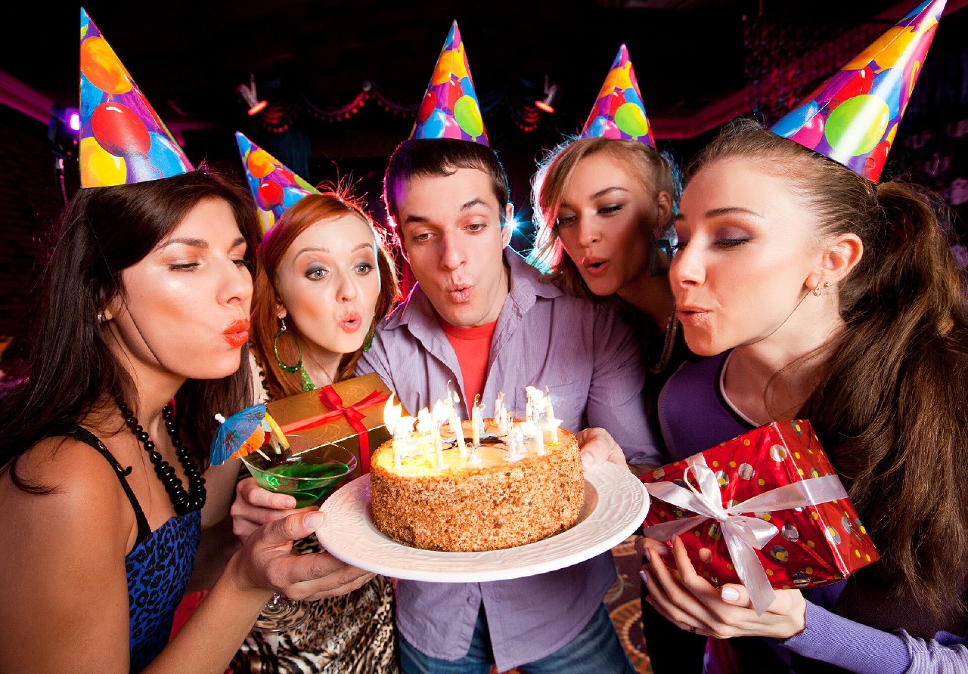 一群年轻的人吹灭生日蛋糕上的蜡烛吹灭蛋糕上的蜡烛的人