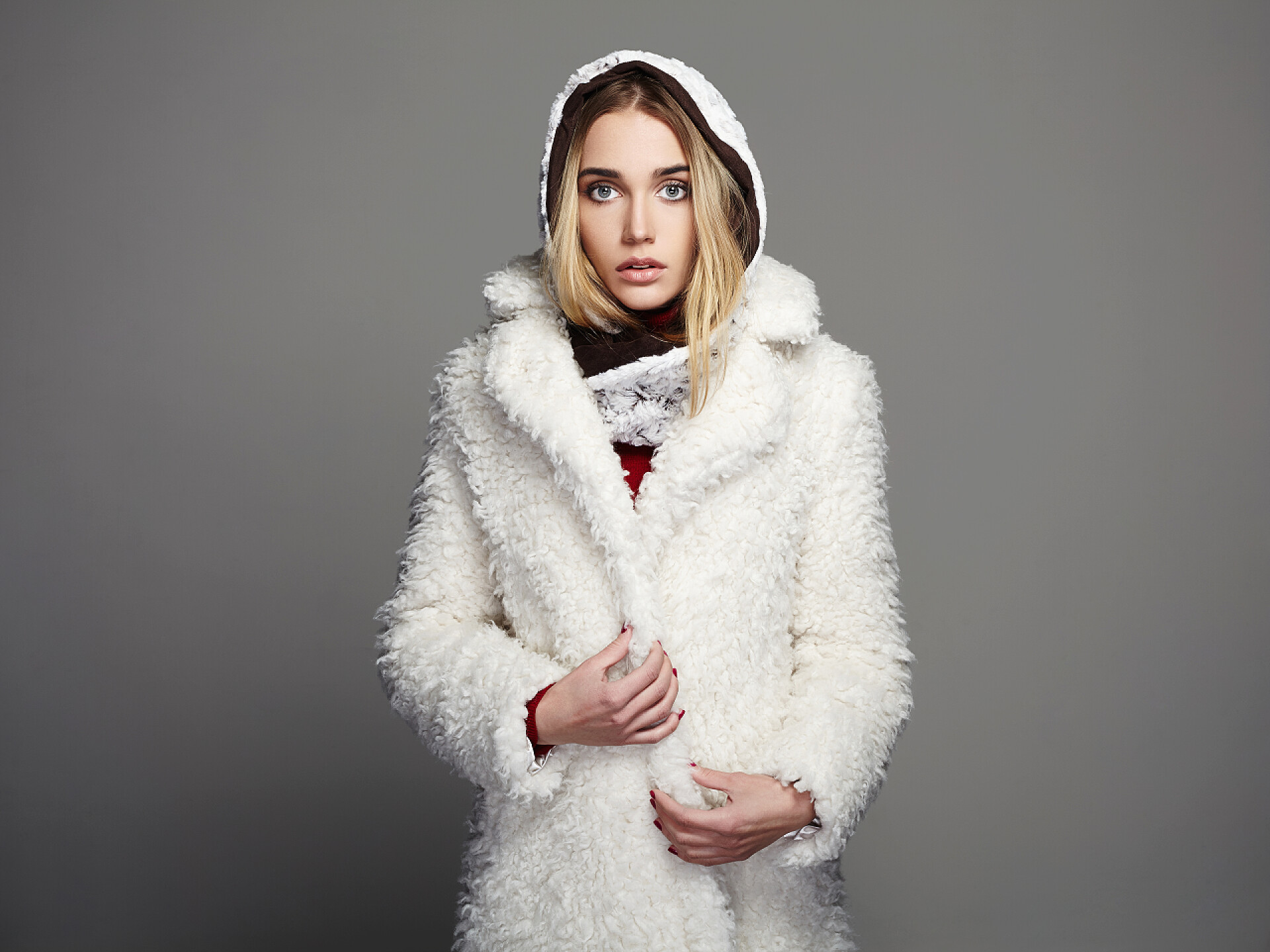 灰色背景下的冬季时尚美少妇在白色毛皮大衣和敞篷的漂亮女孩。冬天的年轻女人
