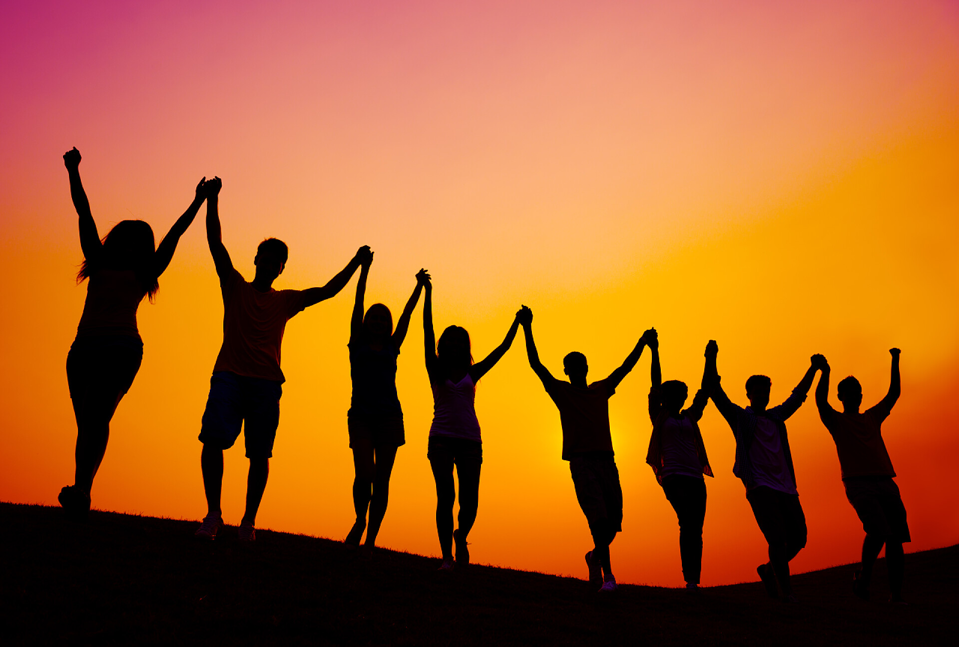 日落时庆祝成功的人们剪影在日落庆祝成功的人