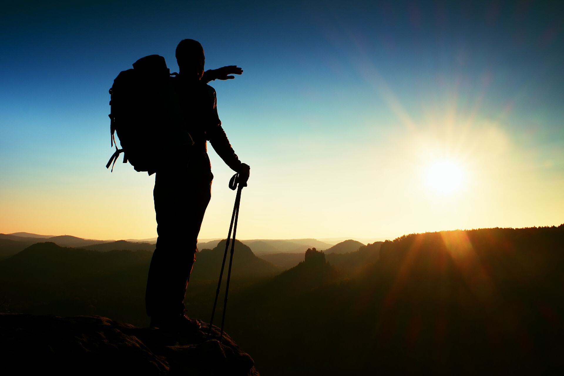徒步旅行者登上山顶看日落锋利的高个子山顶与太阳在框架中的剪影。山区旅游指南