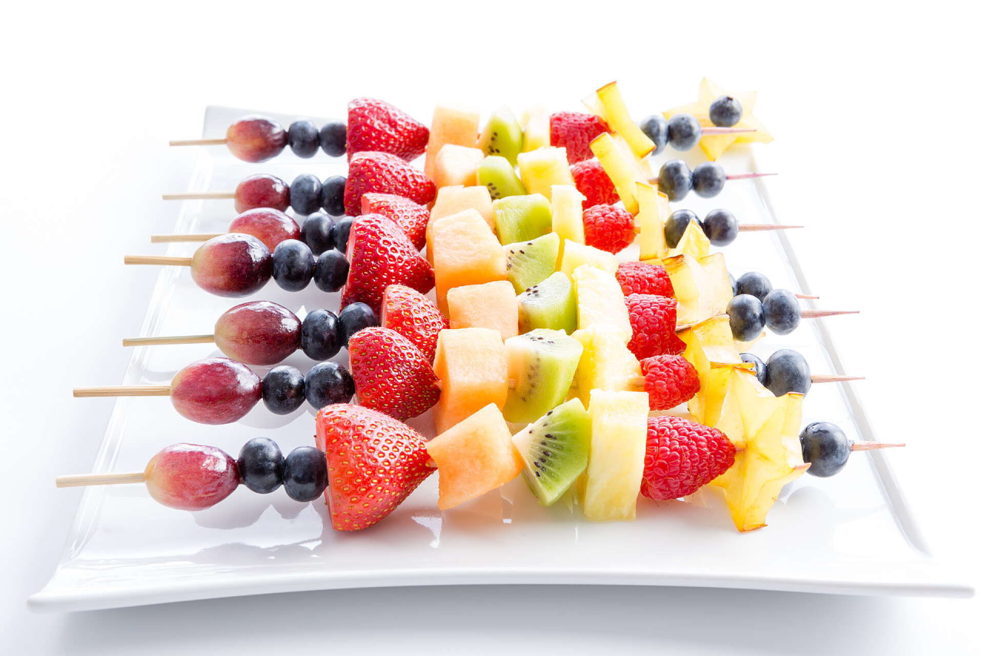 白色背景一盘水果串Serving of colorful fresh fruit kebabs