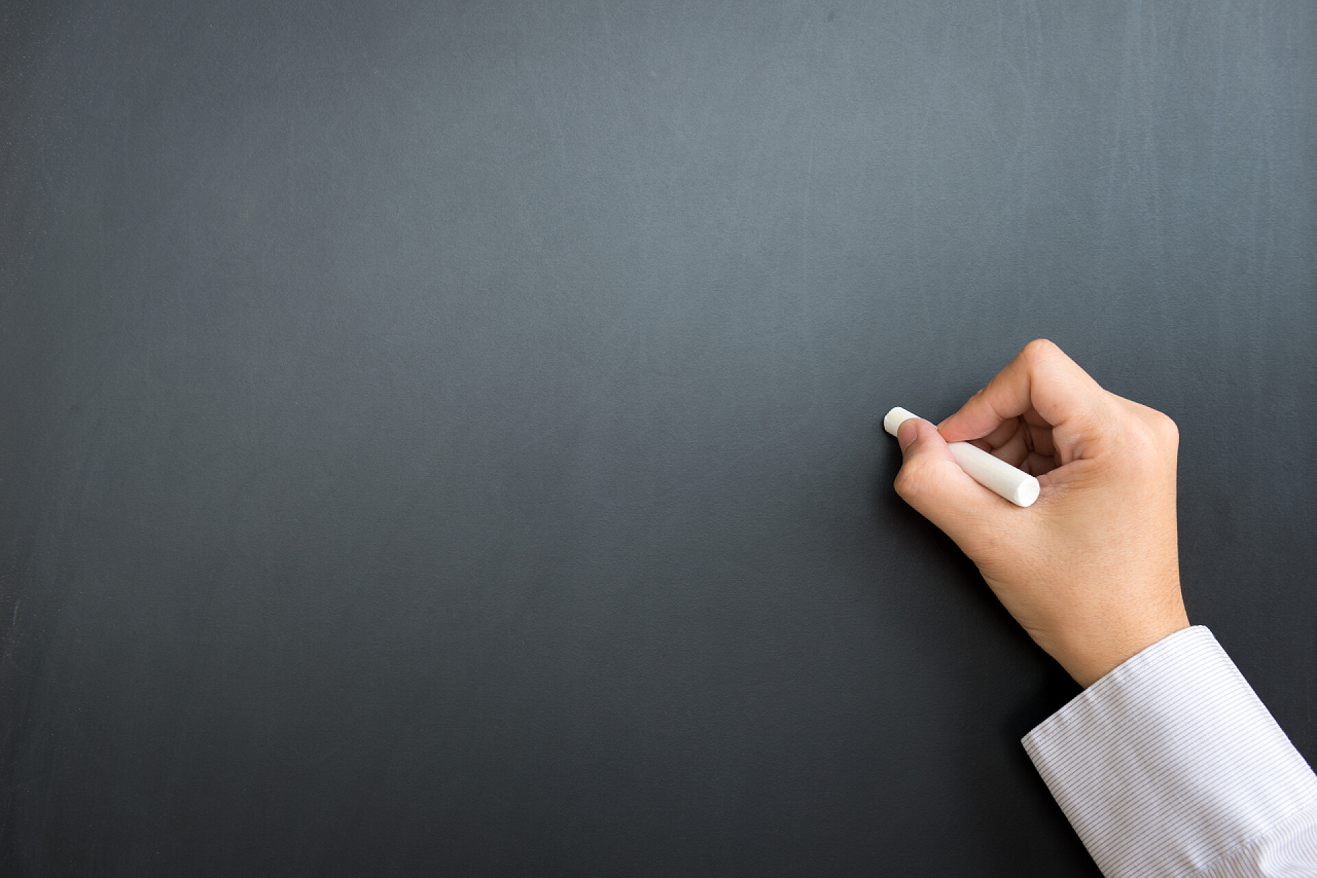 商人手拿着粉笔在空黑板上写字空白的黑色板，用手和粉笔