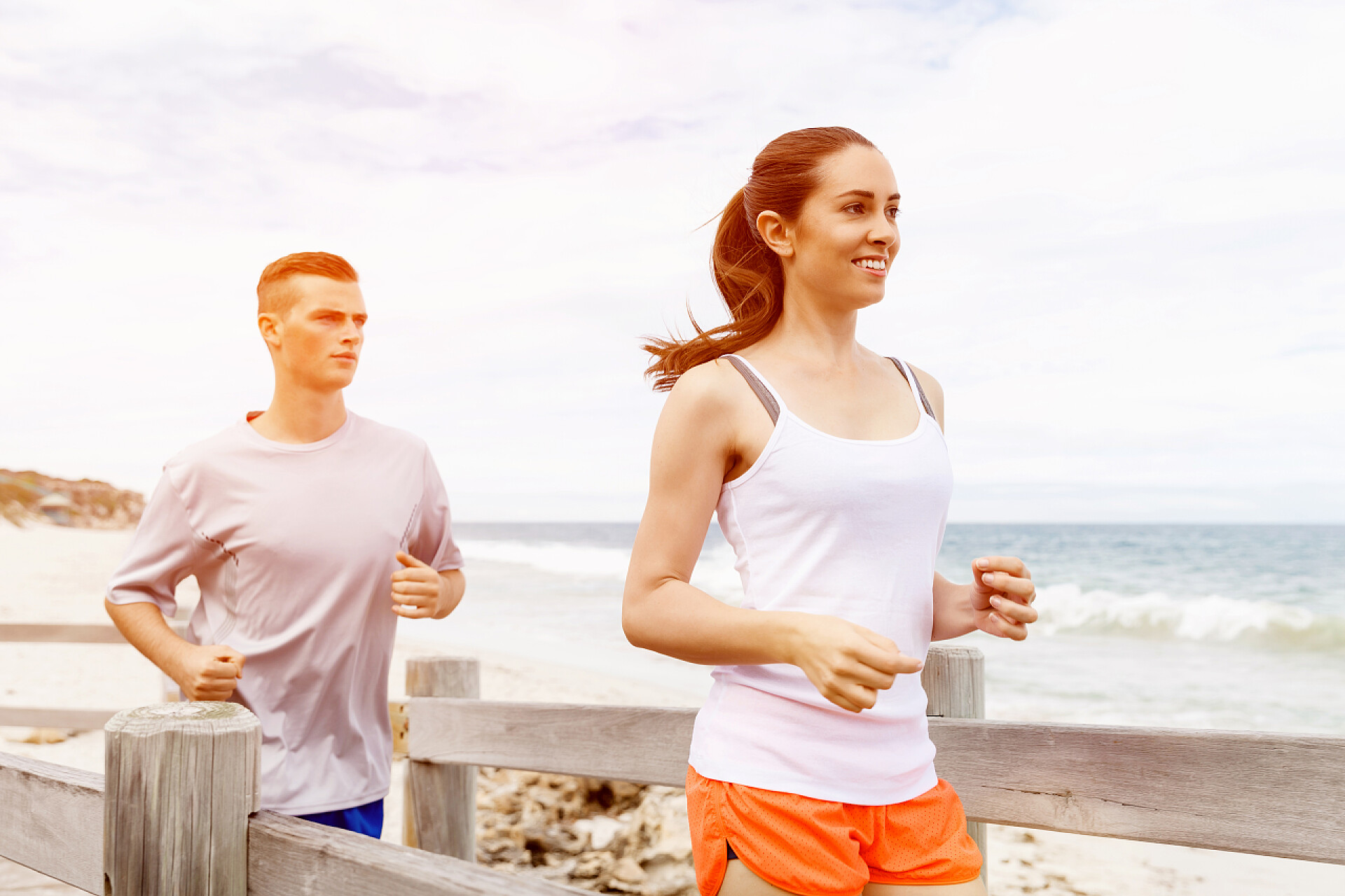 年轻夫妇一起在海滩上跑步赛跑者。年轻的夫妇在海滩上运行