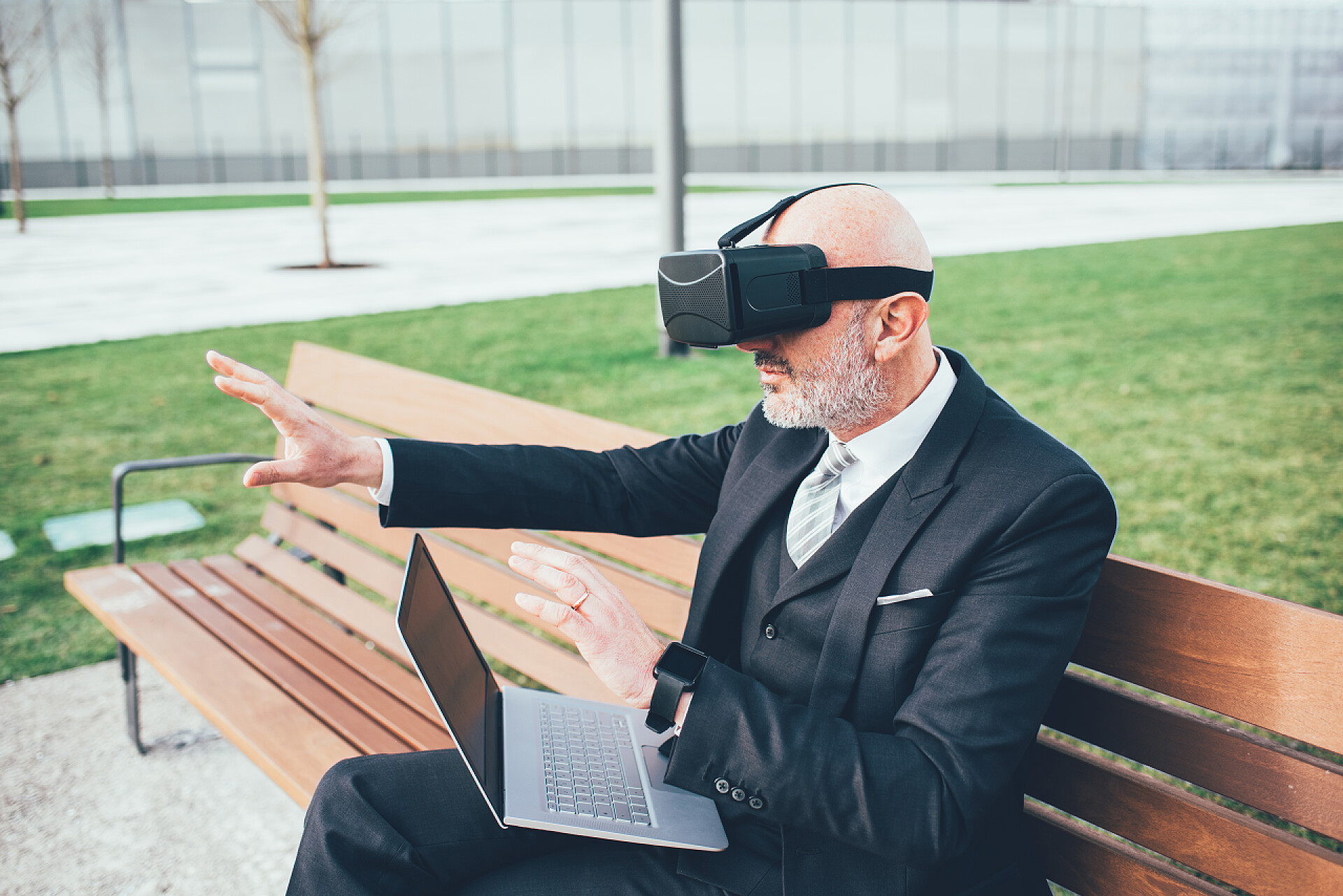 坐在长椅上使用笔记本电脑的商人