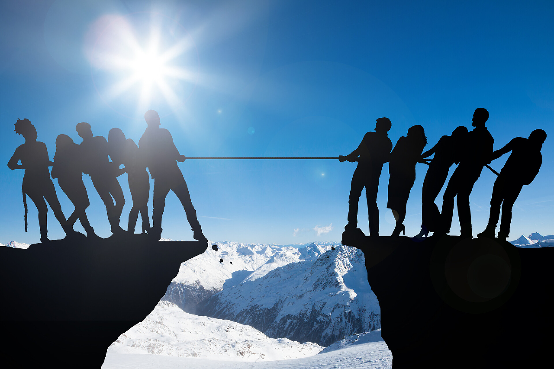 人们在悬崖上玩拔河的剪影人们玩拔河