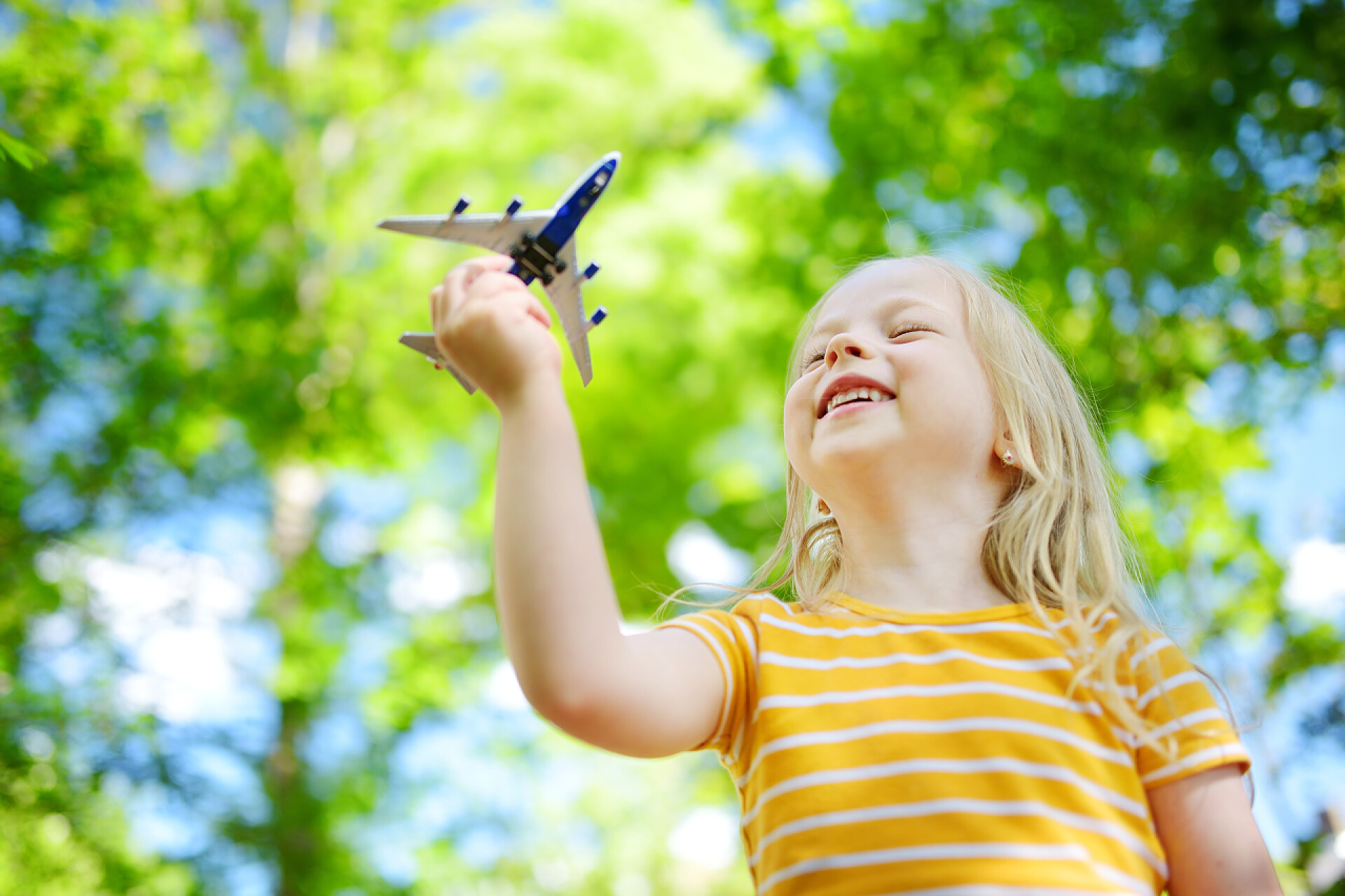 可爱的小女孩在阳光明媚的夏日的户外玩小玩具飞机小女孩玩玩具飞机