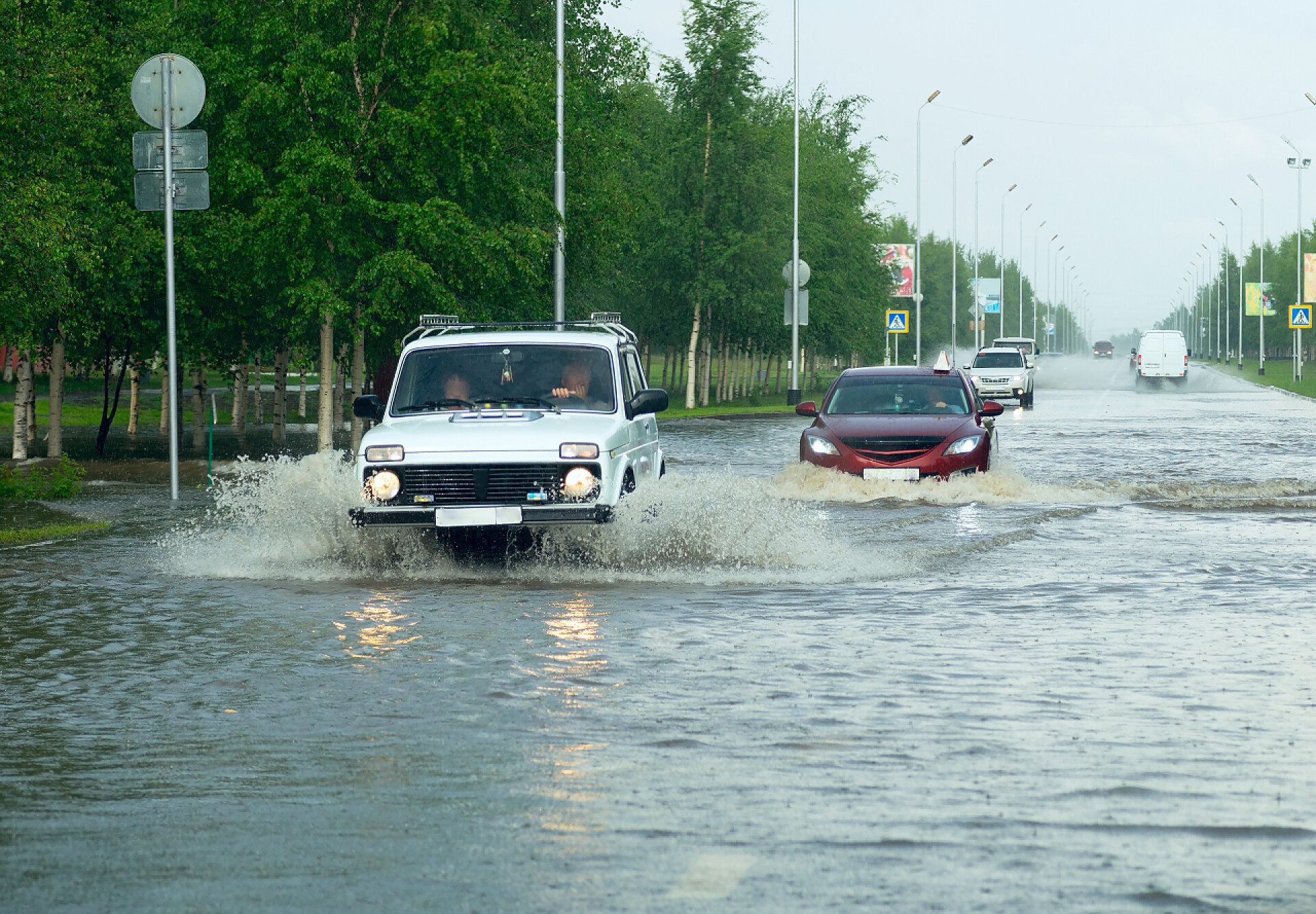 户外白轿车在大雨中行驶道路安全配图汽车穿过城市街道上的一个巨大水坑.
