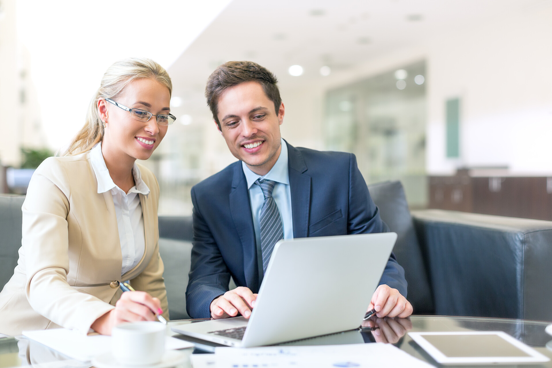 带着手提电脑在办公室微笑的生意人微笑与笔记本电脑的商务人士