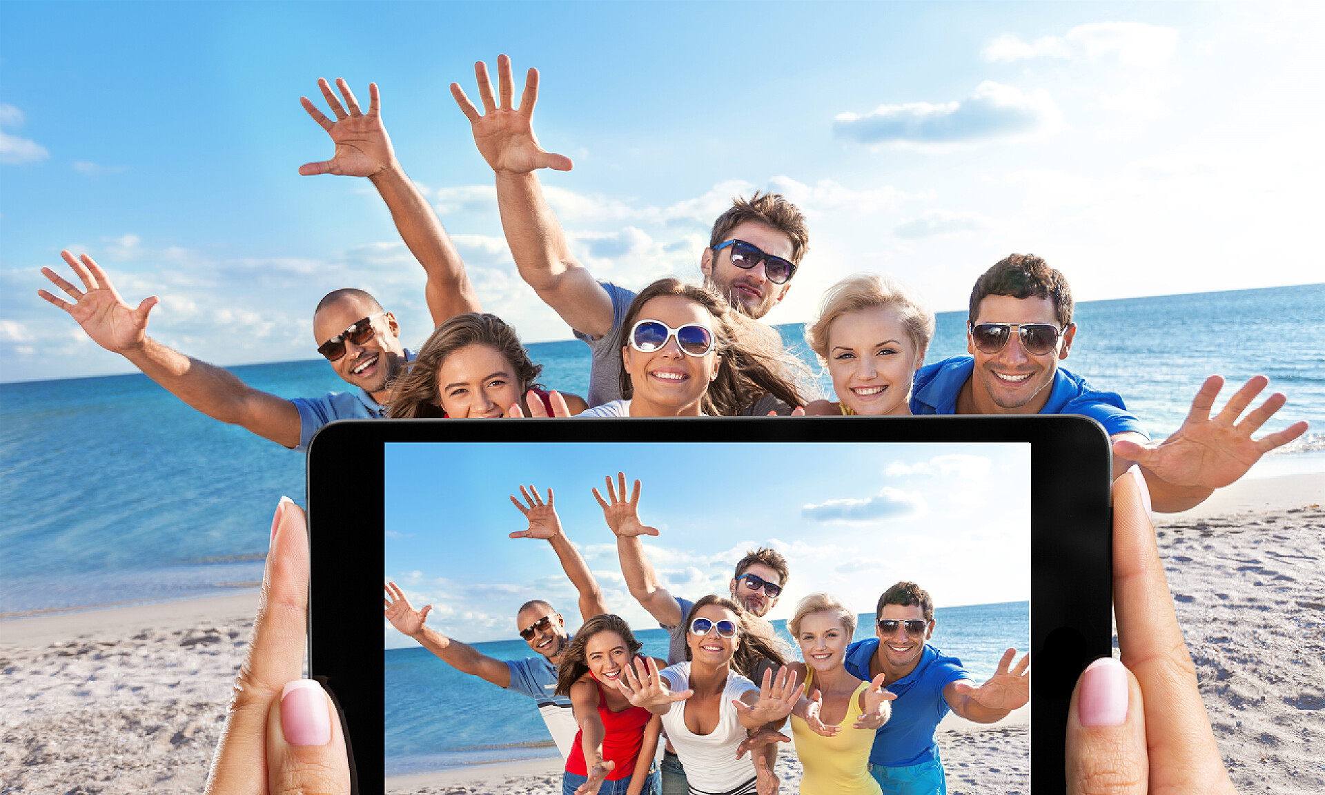 用手机给沙滩上的一群年轻人拍照 一群人站在海滩上