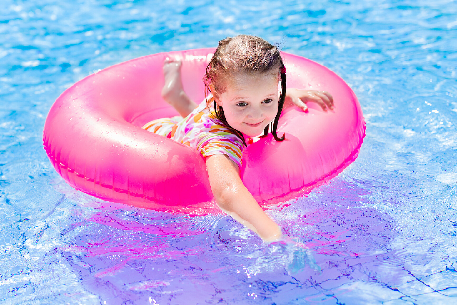 快乐的孩子在游泳池里玩耍女孩躺在游泳池里。夏天热和水.