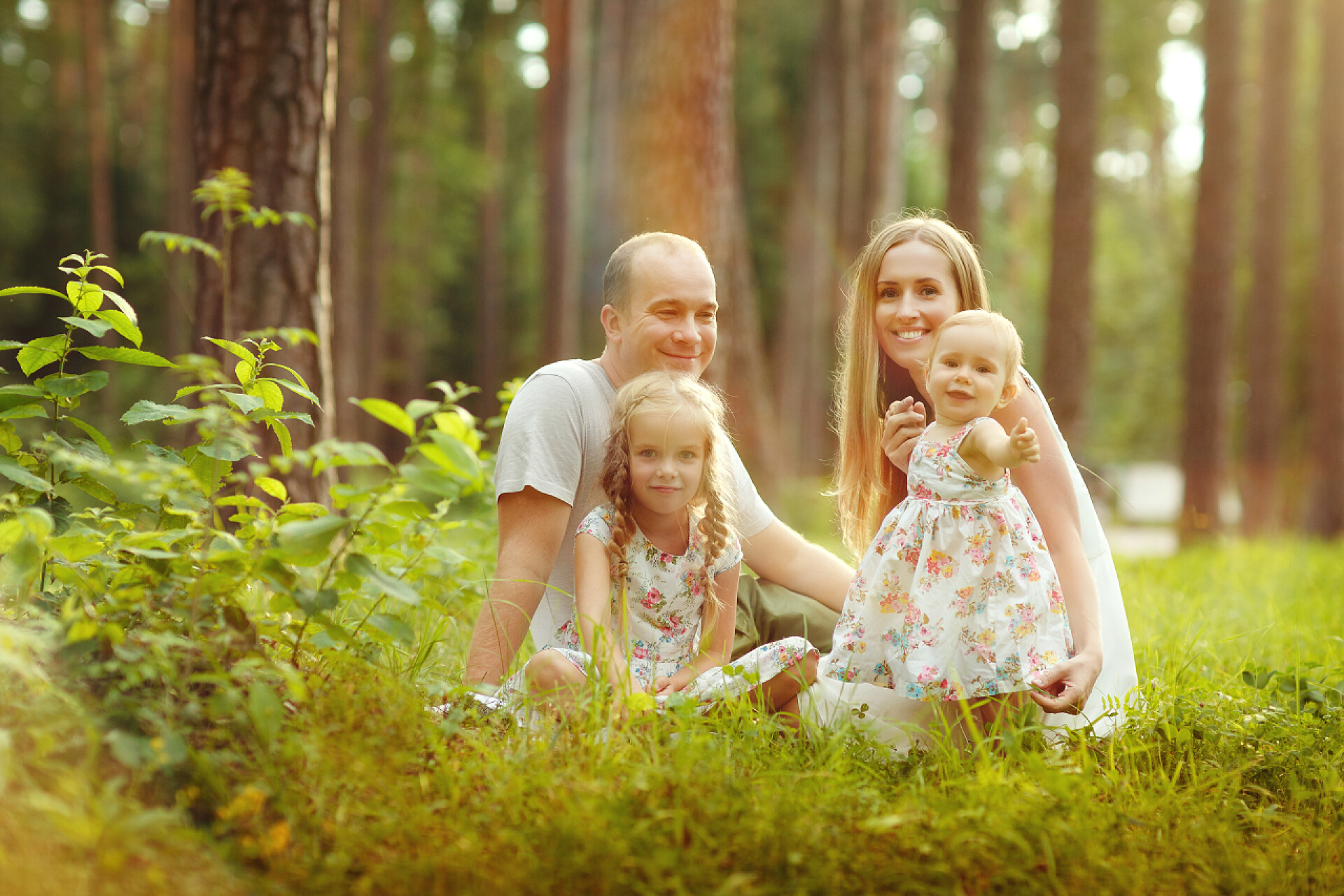 在户外玩耍的一家四口家庭 — — 母亲、 父亲和两个女儿金发女郎坐在苏