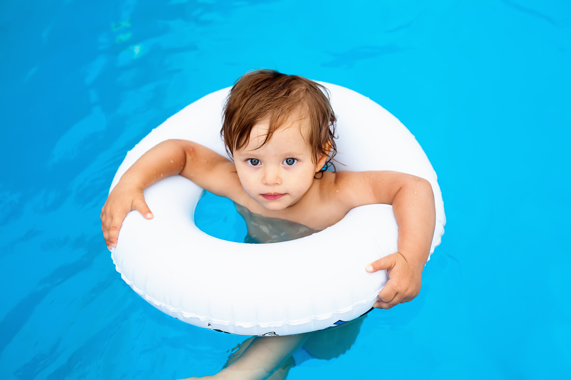 室外游泳池里带着游泳圈玩耍的儿童婴儿在游泳池游泳