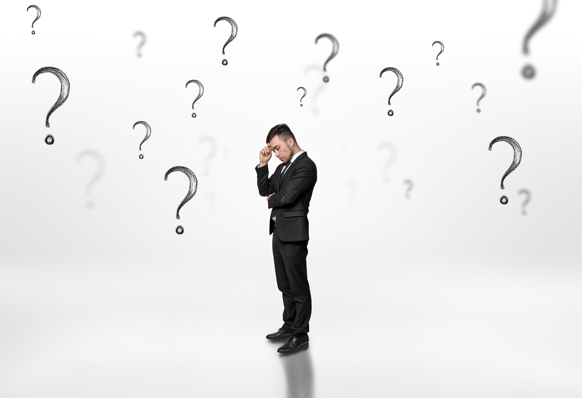 被白色背景上的问号包围的商人周到的商人看向上包围在白色背景上的问号