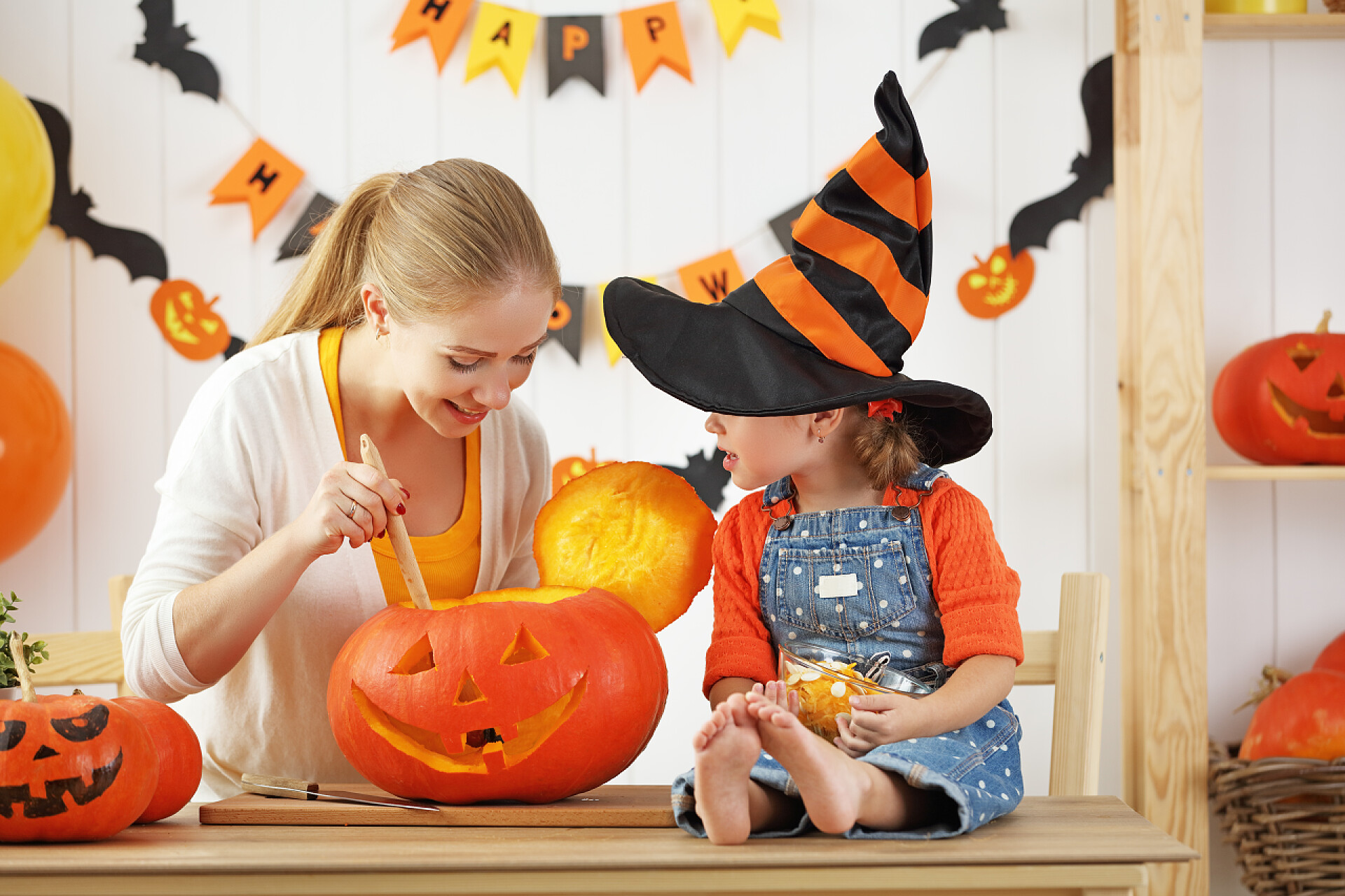 正在做万圣节南瓜灯的母女 家庭的母亲和孩子的女儿正在为万圣节做准备