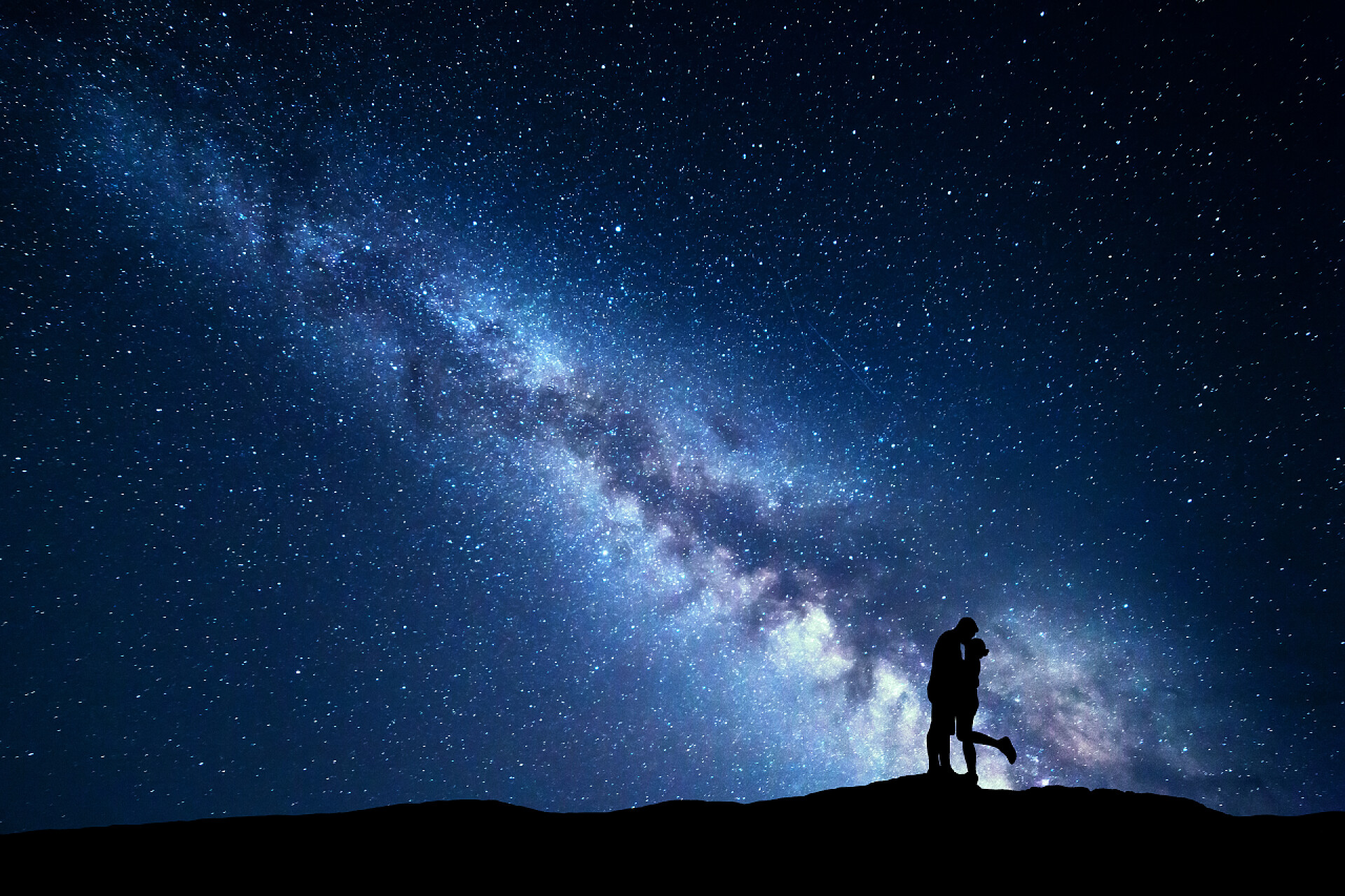 夜晚星空下的人Milky Way. Silhouettes of hugging and kissing man and woman