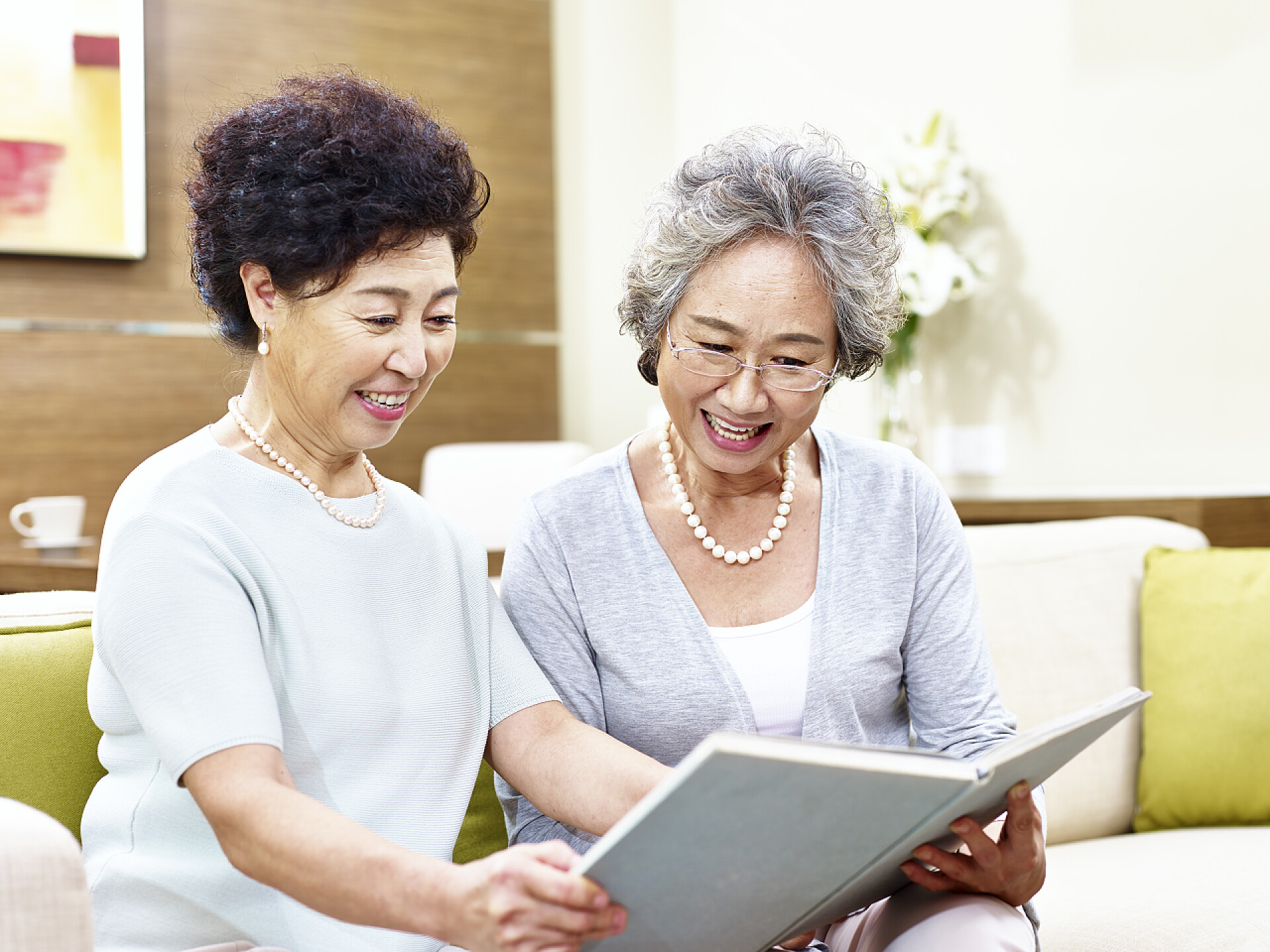 妇女坐在沙发上一起看书两个高级亚洲妇女一起阅读一本书