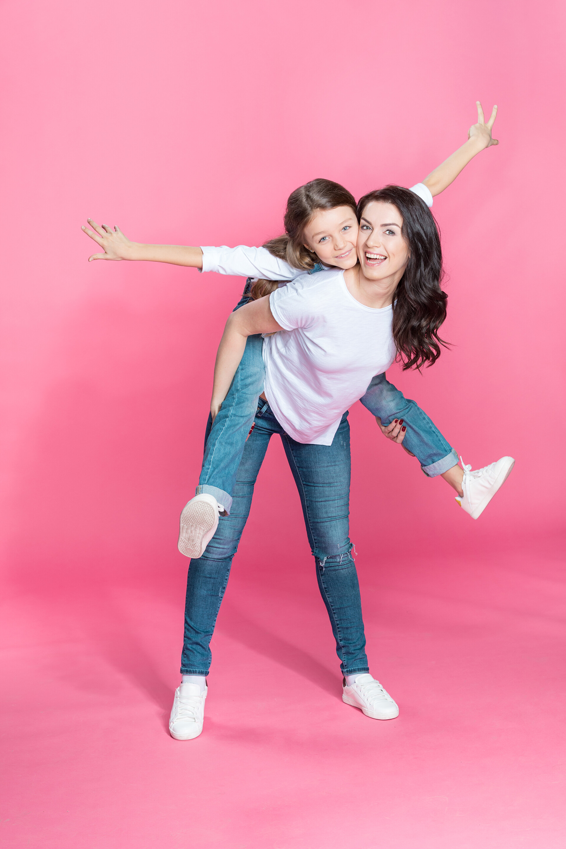 玫红色背景上的快乐母女妈妈和女儿拥抱 