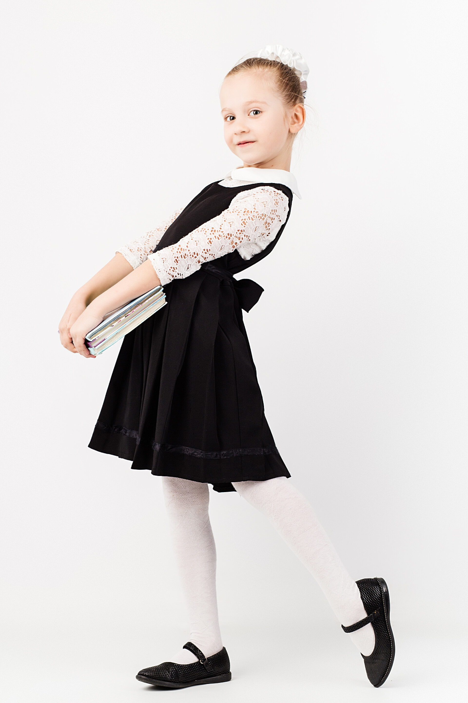 白色背景上拿着书的小女孩特写戴眼镜的搞笑小女孩模仿一个严格的老师，白色背景。小留学生看着照相机。学校的概念。回到学校